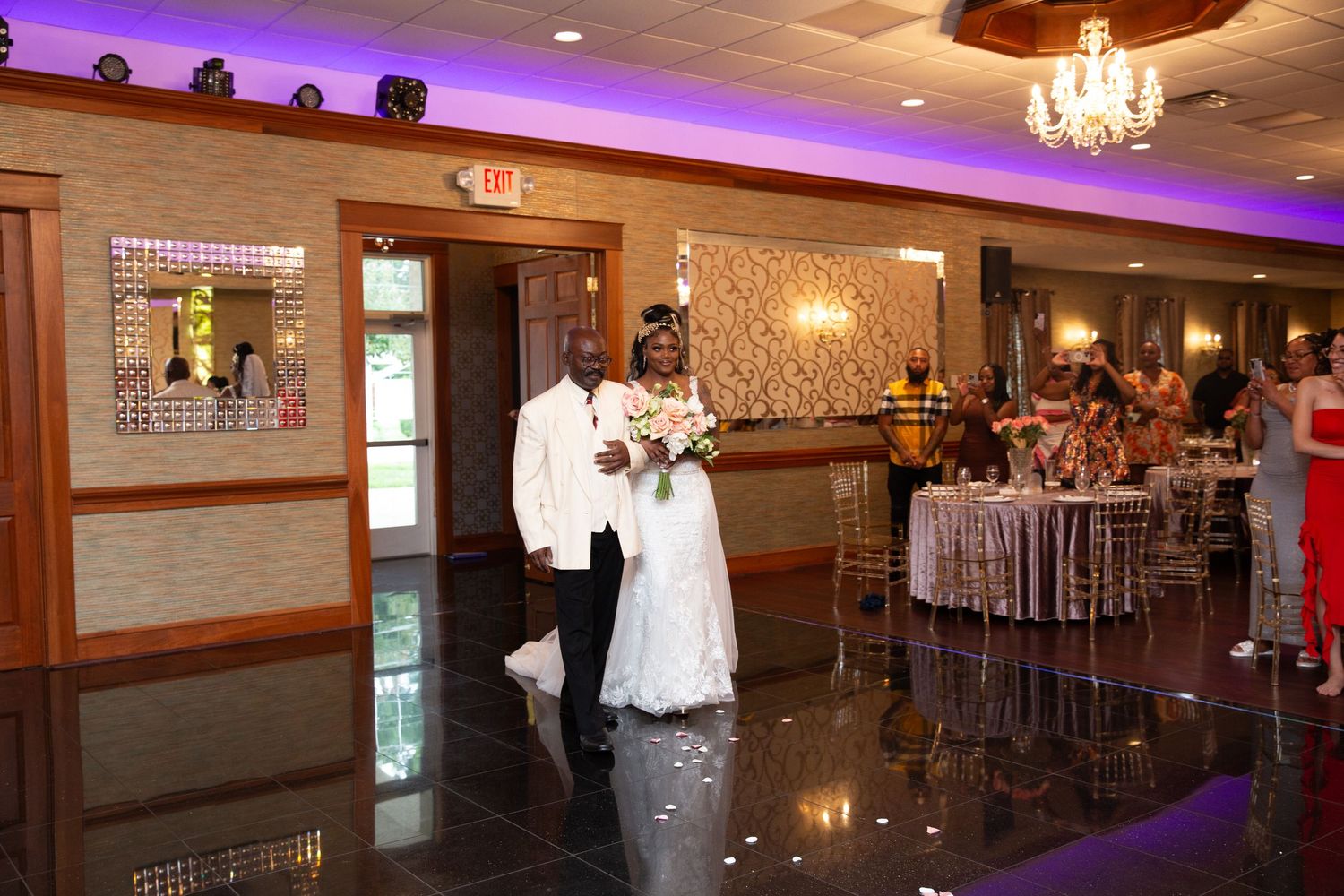 Panoramic view of wedding reception venue with purple lighting and elegant decor.