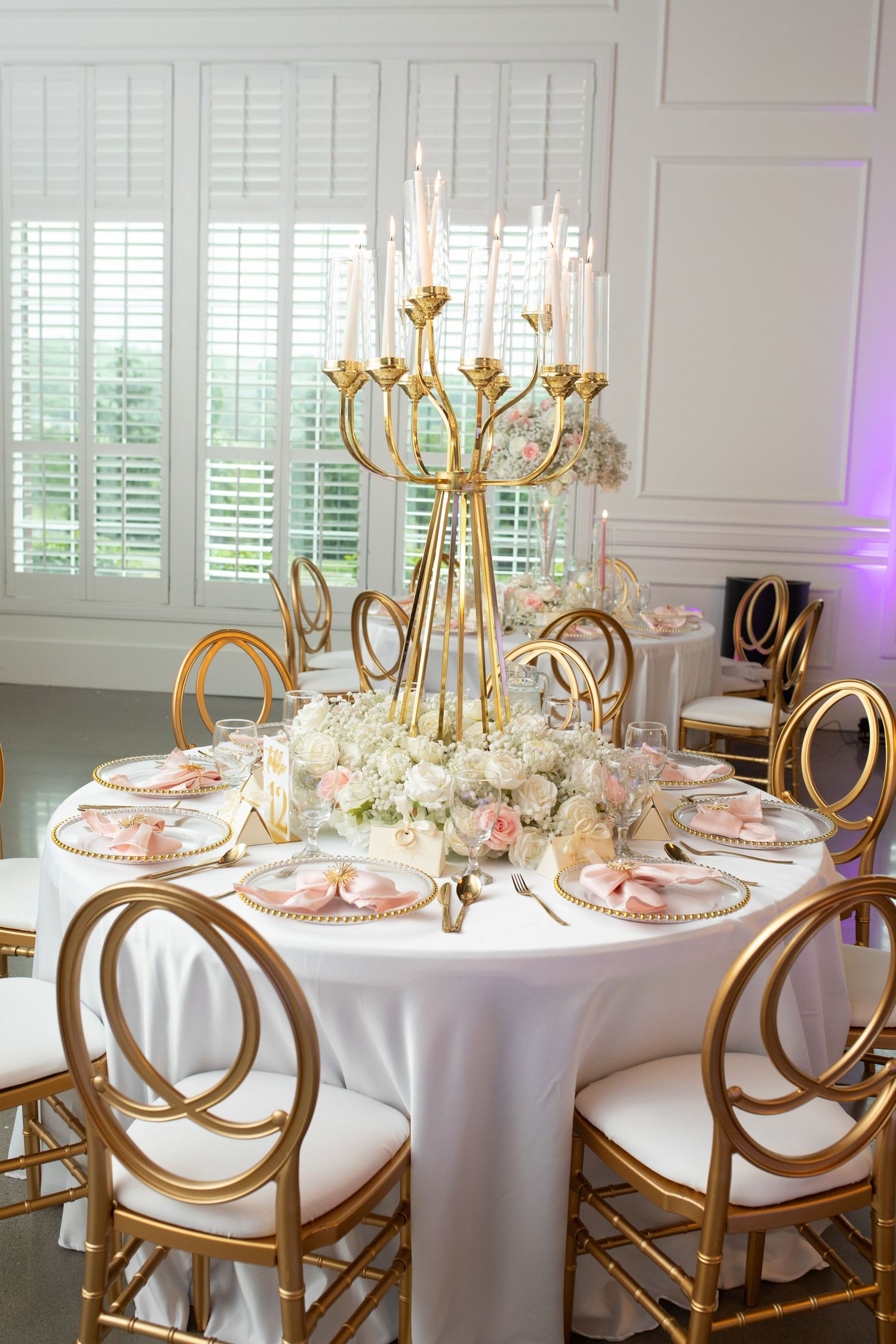 Luxurious wedding reception table with gold candelabra centerpiece and elegant place settings.