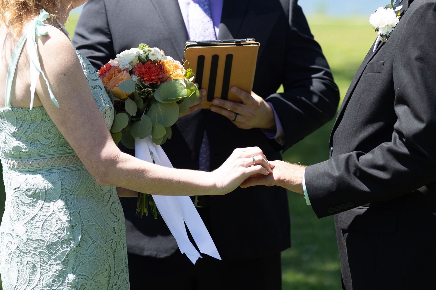 Couple sharing a tender moment during their wedding ceremony in a grassy outdoor setting.