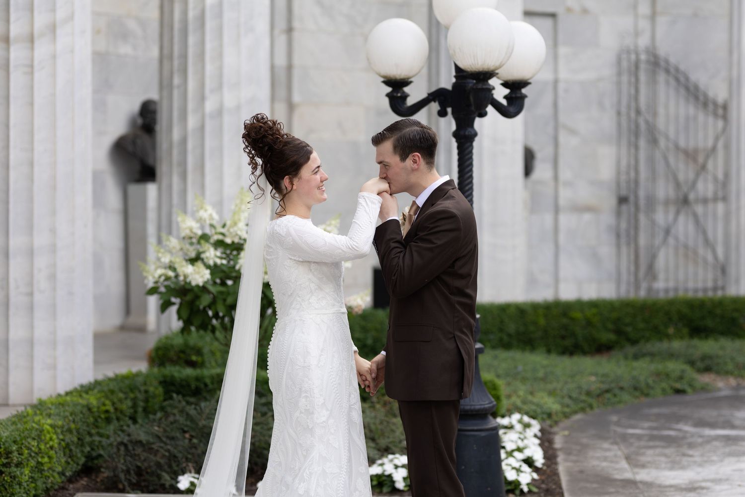 Couple shares tender moment by vintage lamp post against marble columns.