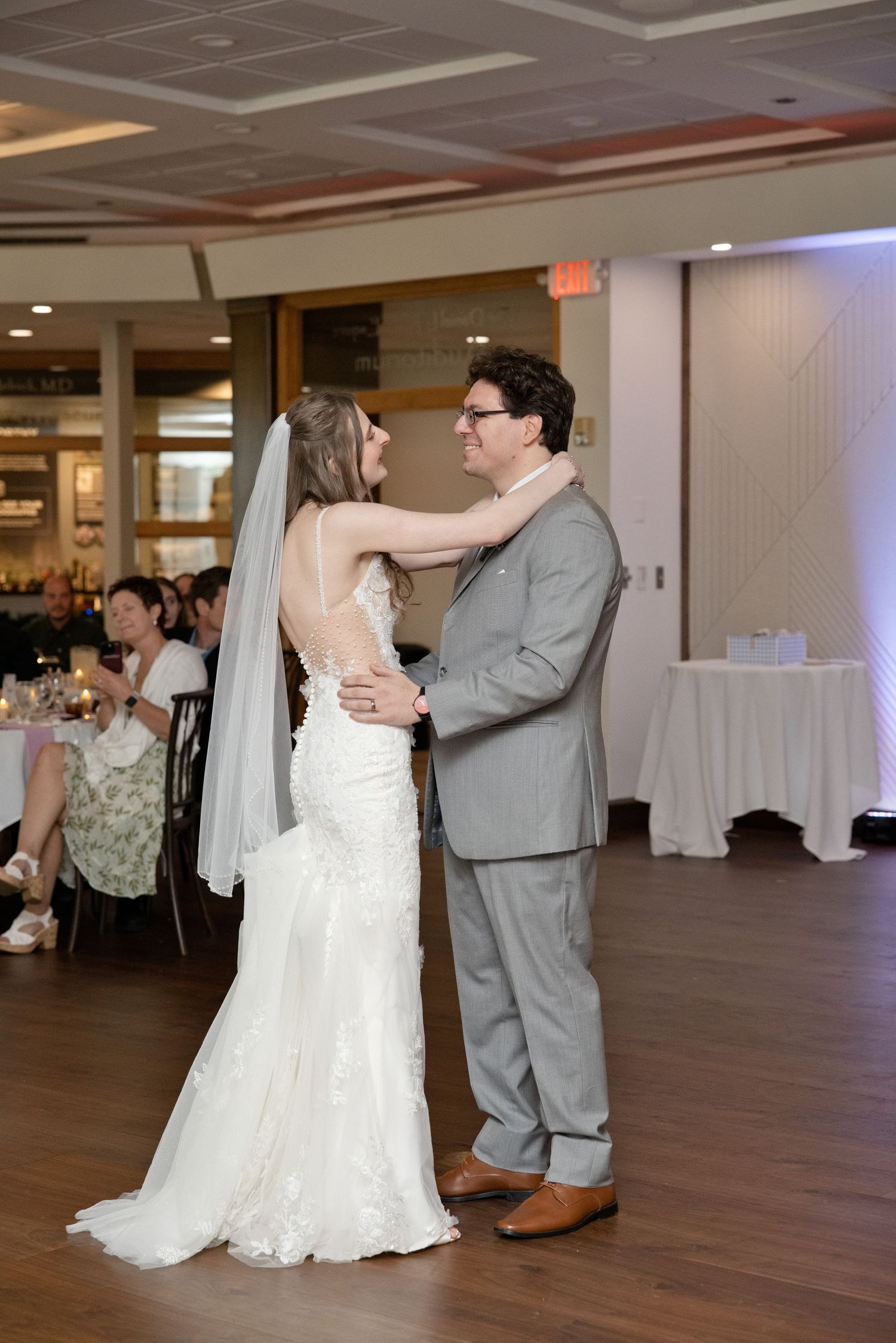 Bride and groom share first dance in wedding venue, bride wearing lace mermaid gown with veil.