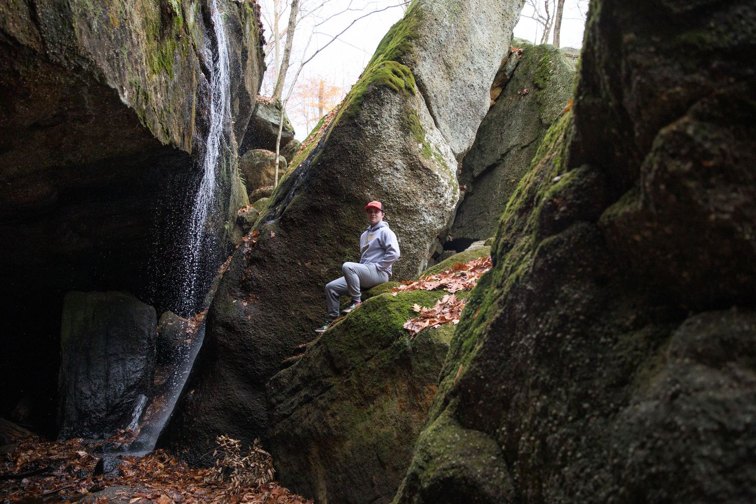 Rocky cliff formations covered in moss along a hiking trail in the woods.