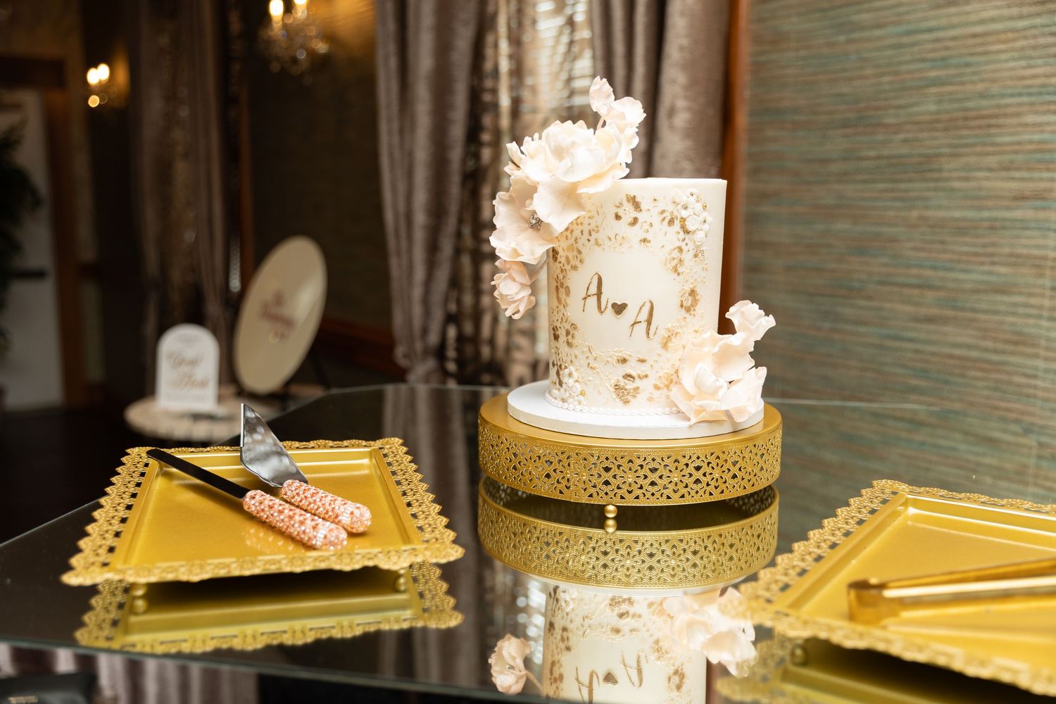 Wedding cake displayed on a gold stand with elegant white decorative details.