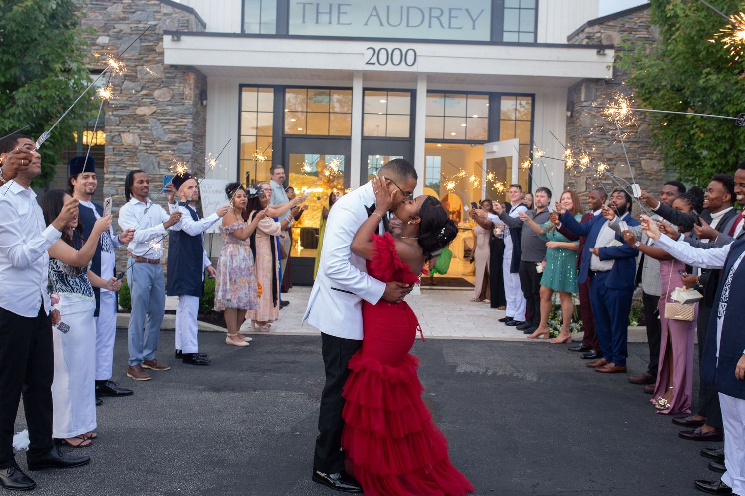 Couple embracing during twilight sendoff surrounded by cheering guests at The Audrey.