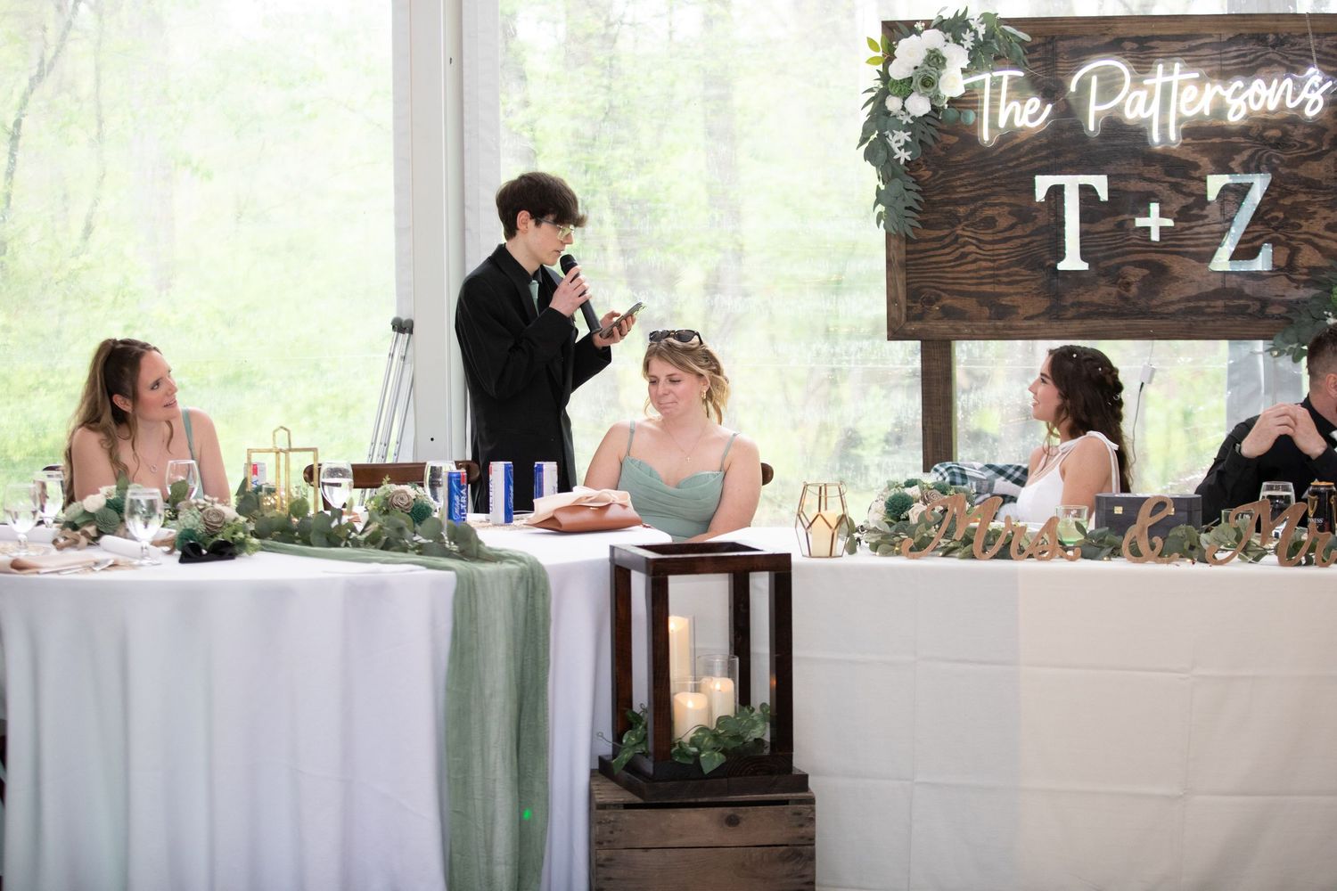 Wedding reception toast at the Pattersons T+Z sweetheart table with floral decor and greenery runner.