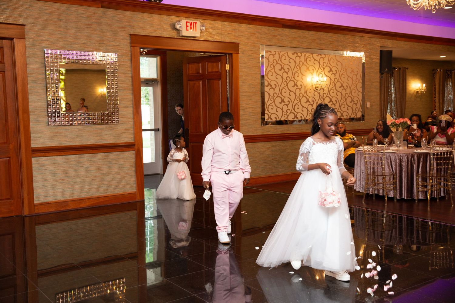 Wedding reception venue with elegant chandeliers and purple accent lighting.