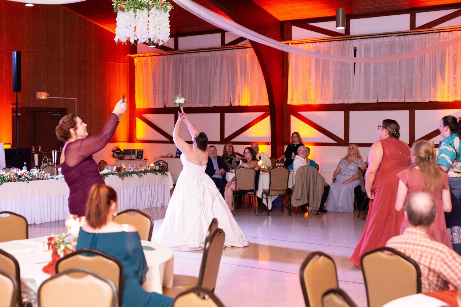 Wedding reception dance floor lit with warm orange lighting and white decor.