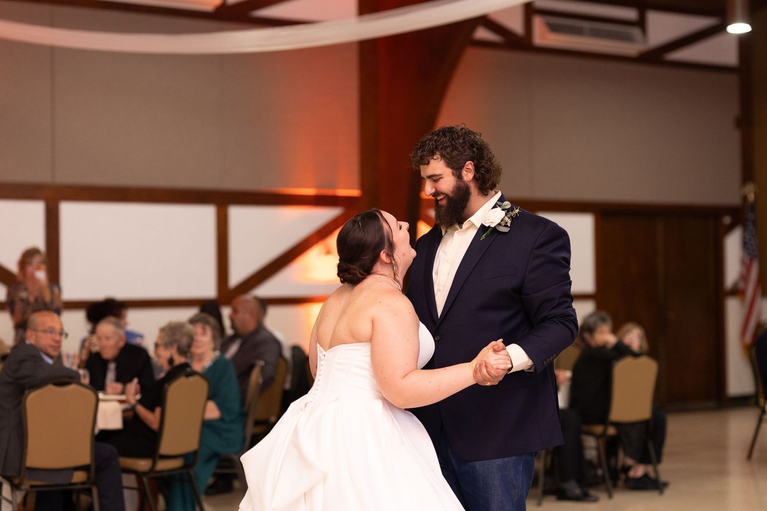Wedding couple performs a romantic dip during their first dance in a reception hall.