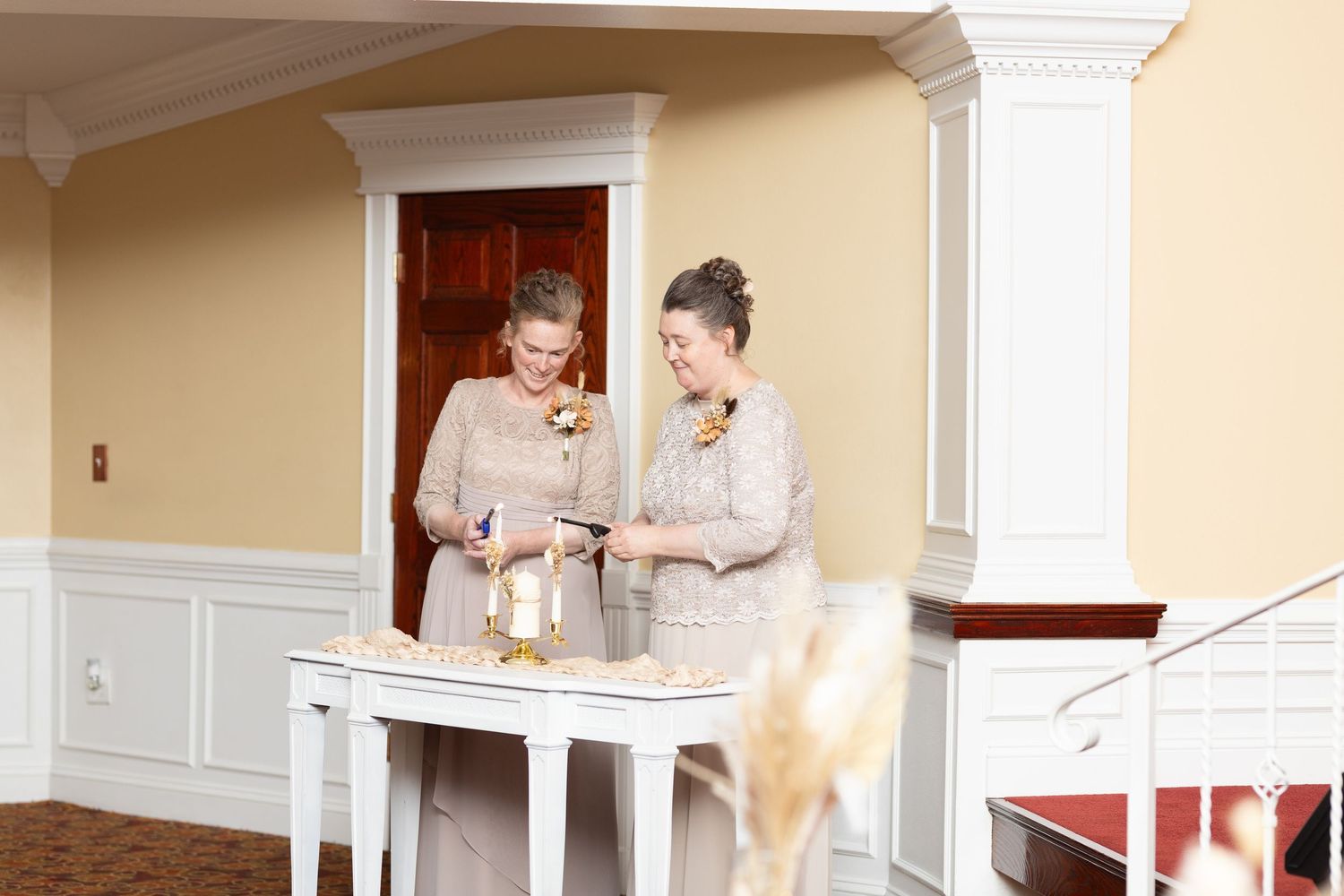 Two people signing documents at a white table in an elegant room setting.