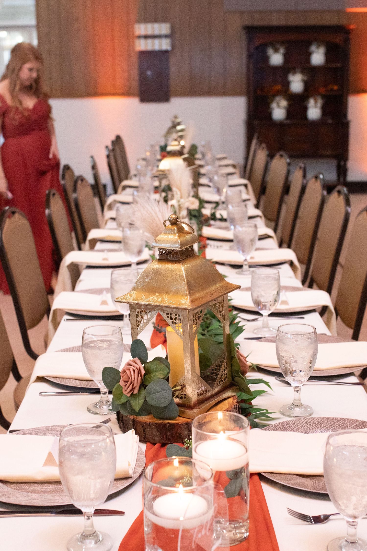An elegant wedding reception table with gold lantern centerpieces and place settings.