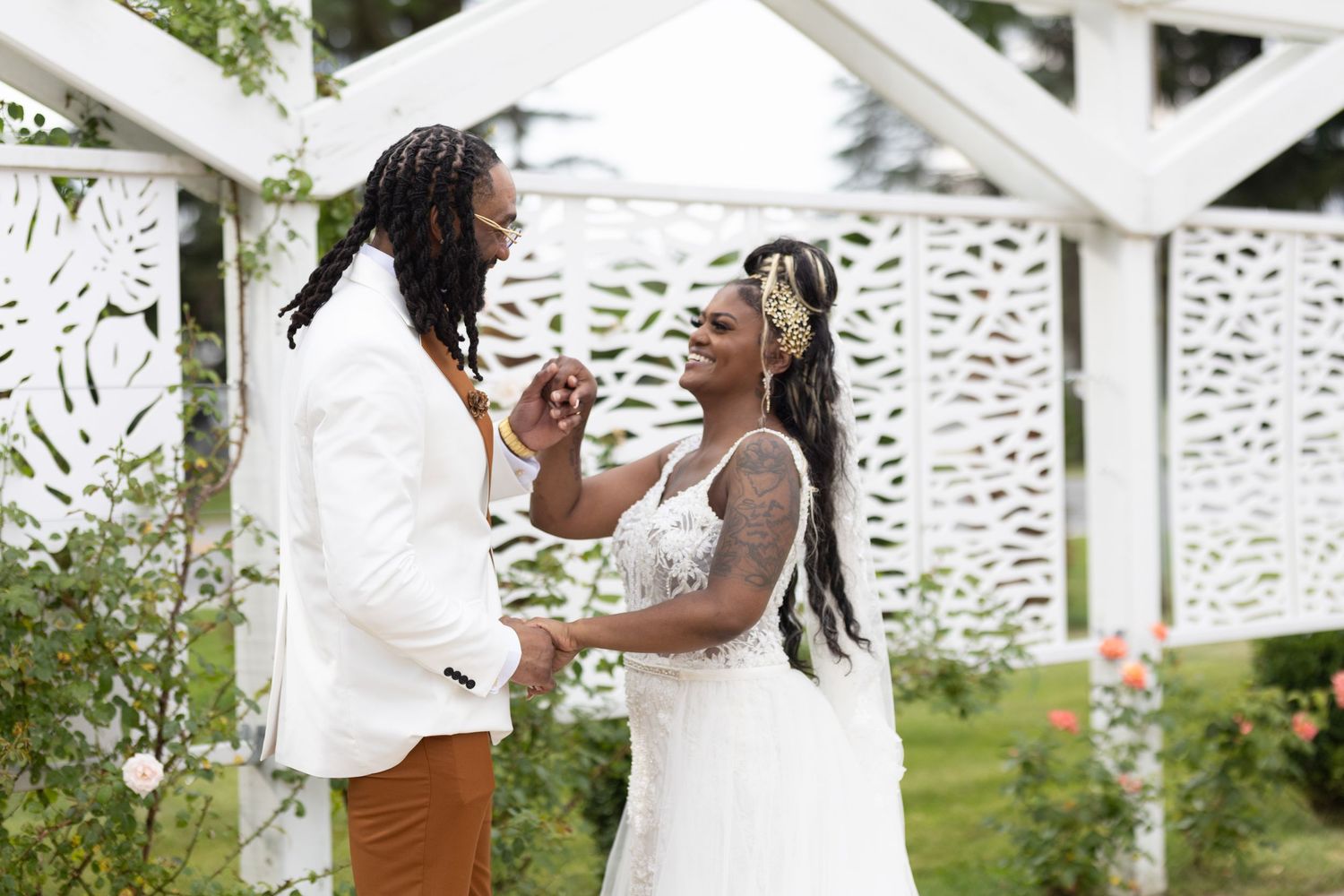 Couple shares intimate moment under white pergola during wedding ceremony.