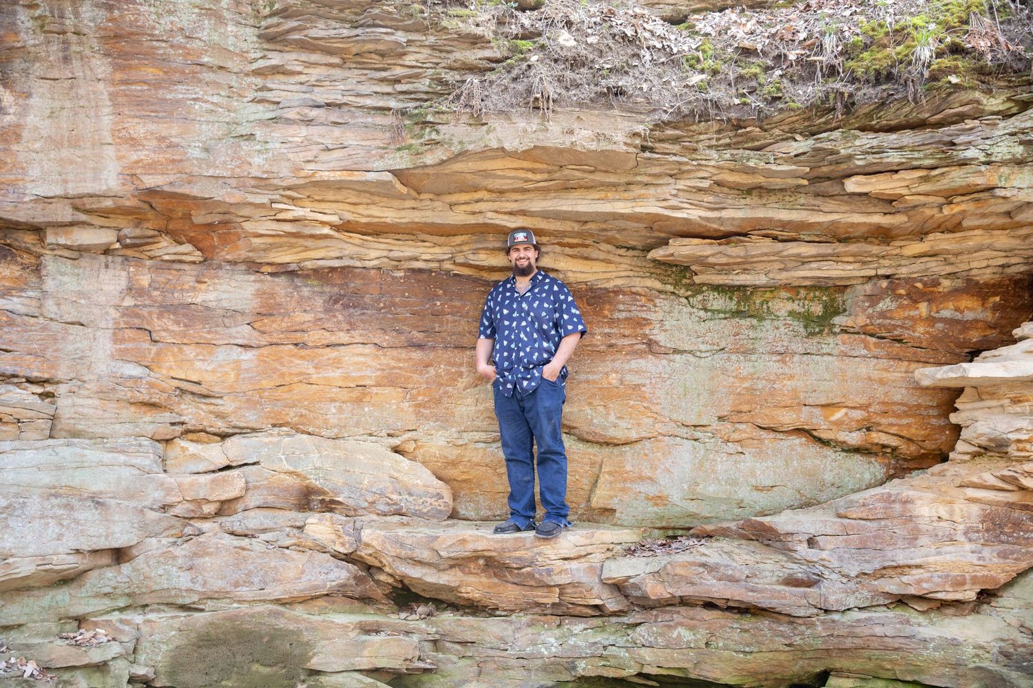 Person standing on layered rock formation with weathered texture.