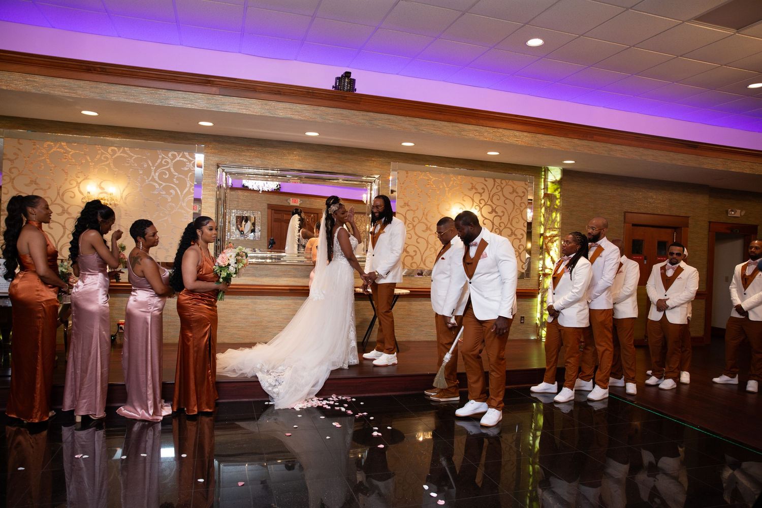 Wedding reception venue decorated with purple uplighting and crystal chandeliers.