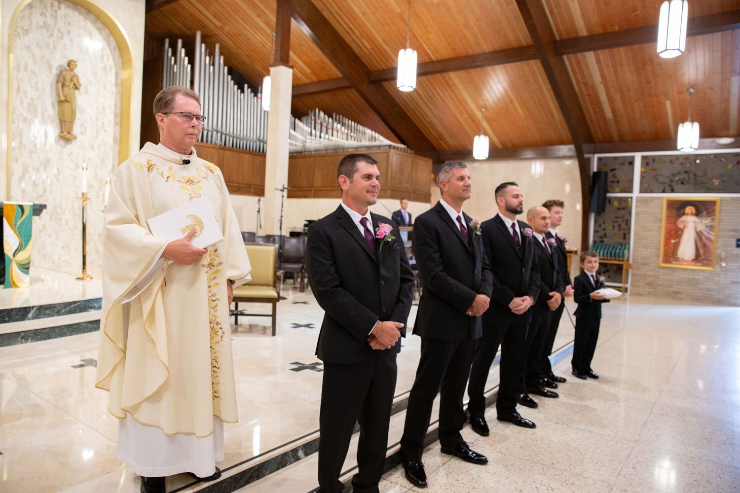 Wedding party members lined up in formal attire inside church sanctuary.