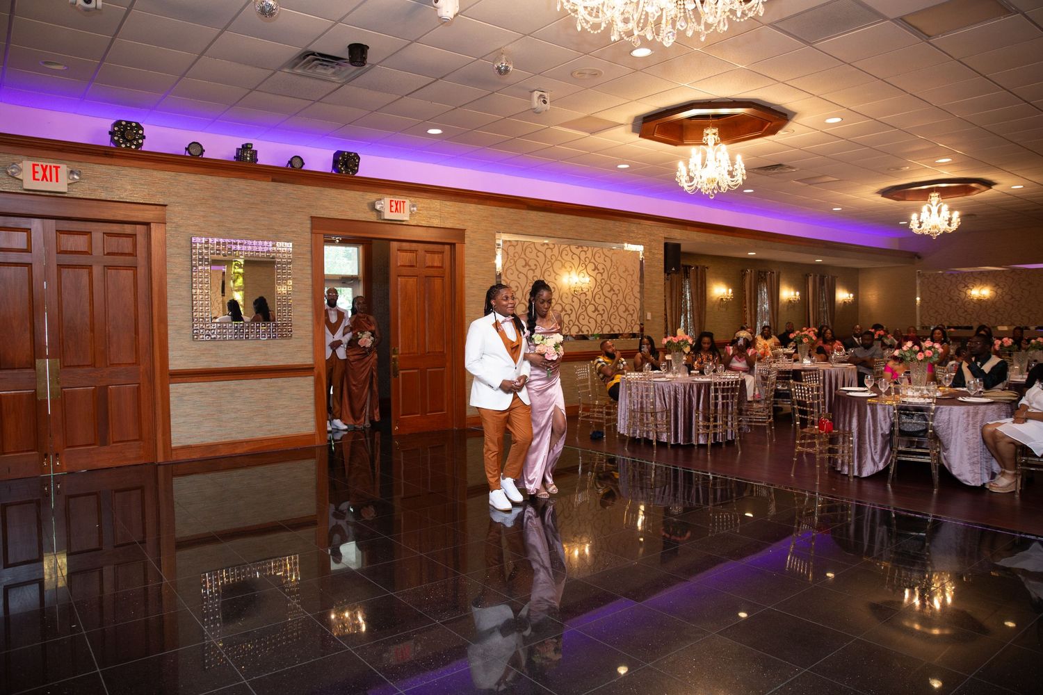 Wedding reception dance floor scene with elegant lighting and wood-paneled walls.