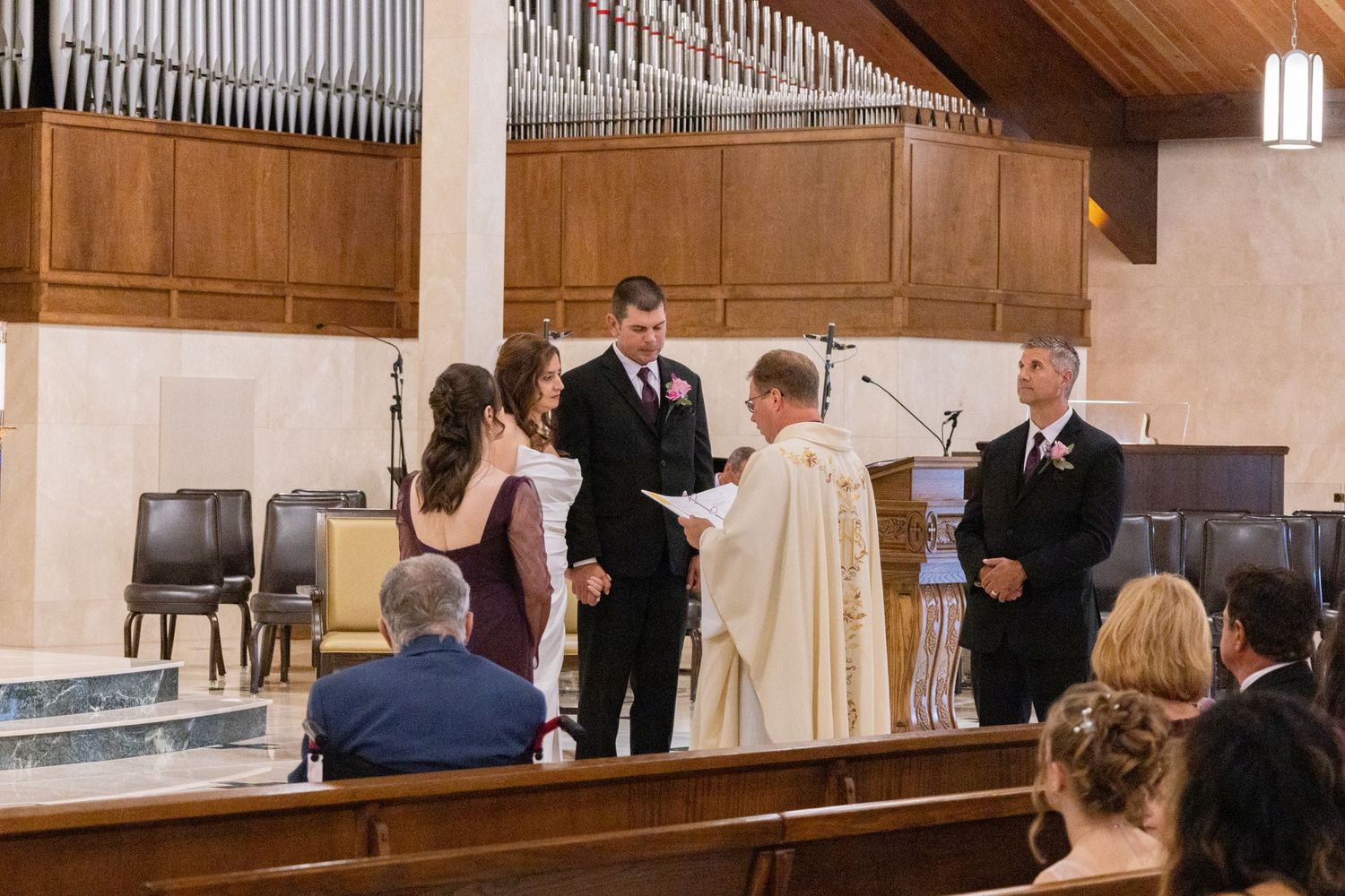 Church interior with wooden beams and organ pipes during wedding ceremony.