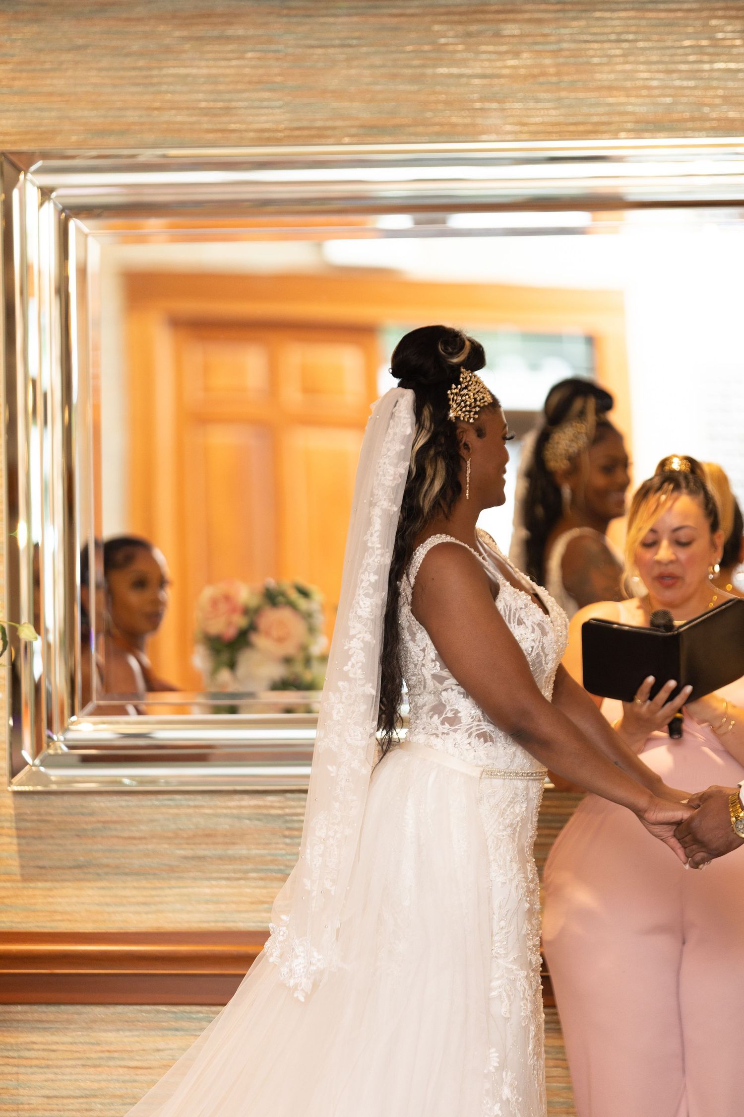 Wedding party members in pink and white attire pose by mirrored wall.