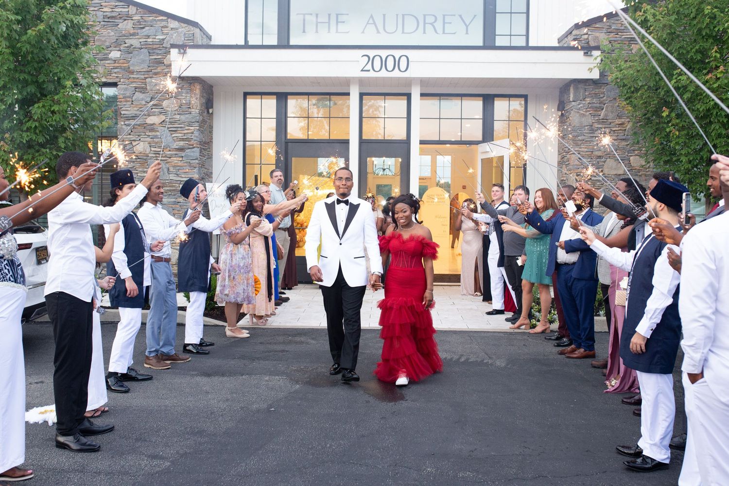 Newlyweds exiting venue while guests form celebratory sendoff line outside The Audrey.