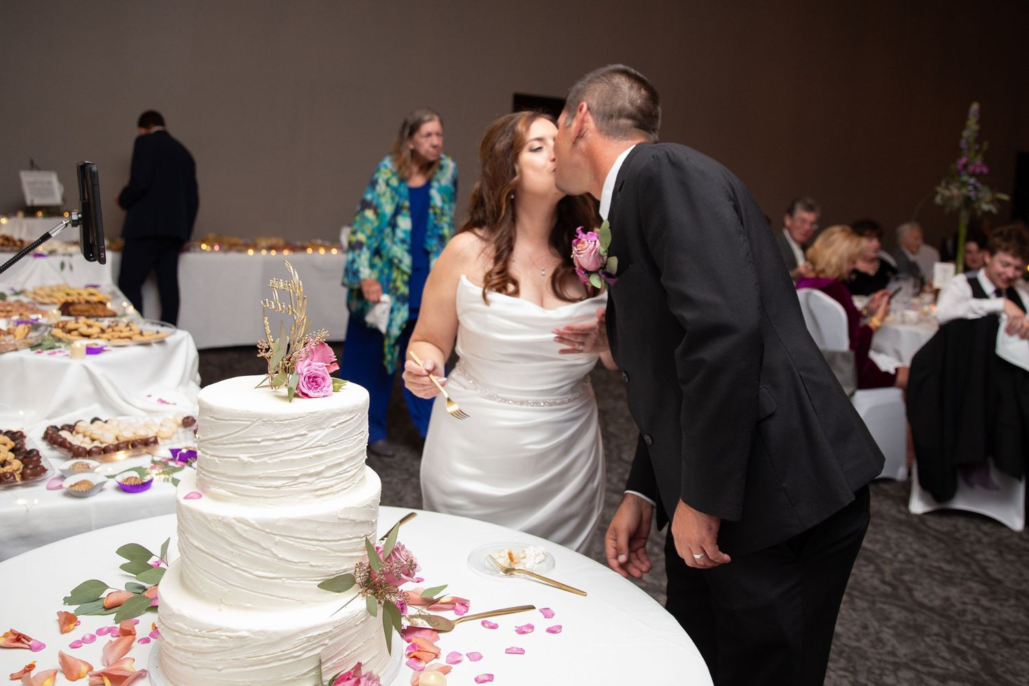 Wedding reception guests gathered around the cake table during the celebration.