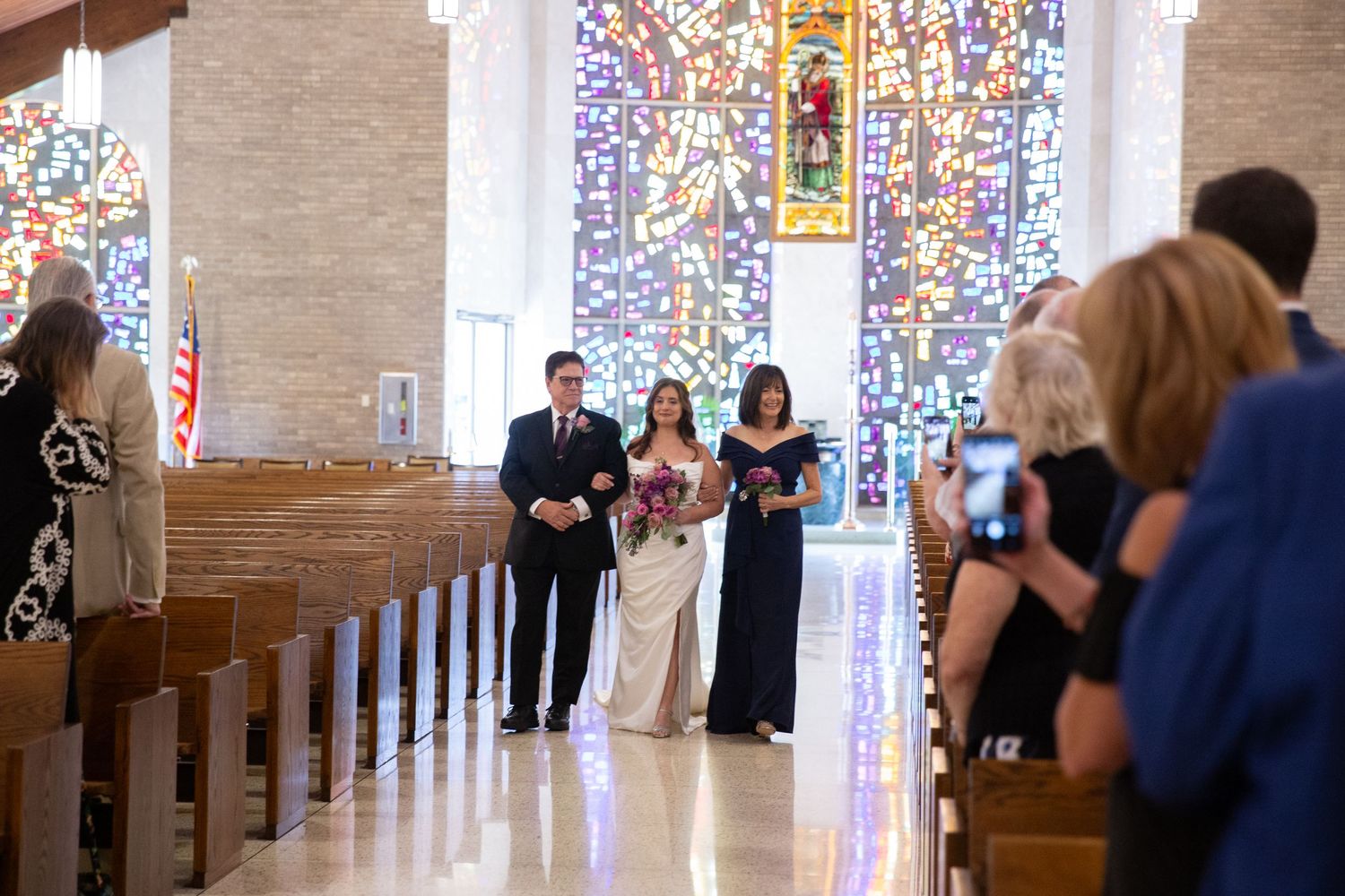 Church interior with stained glass windows and wedding ceremony in progress.