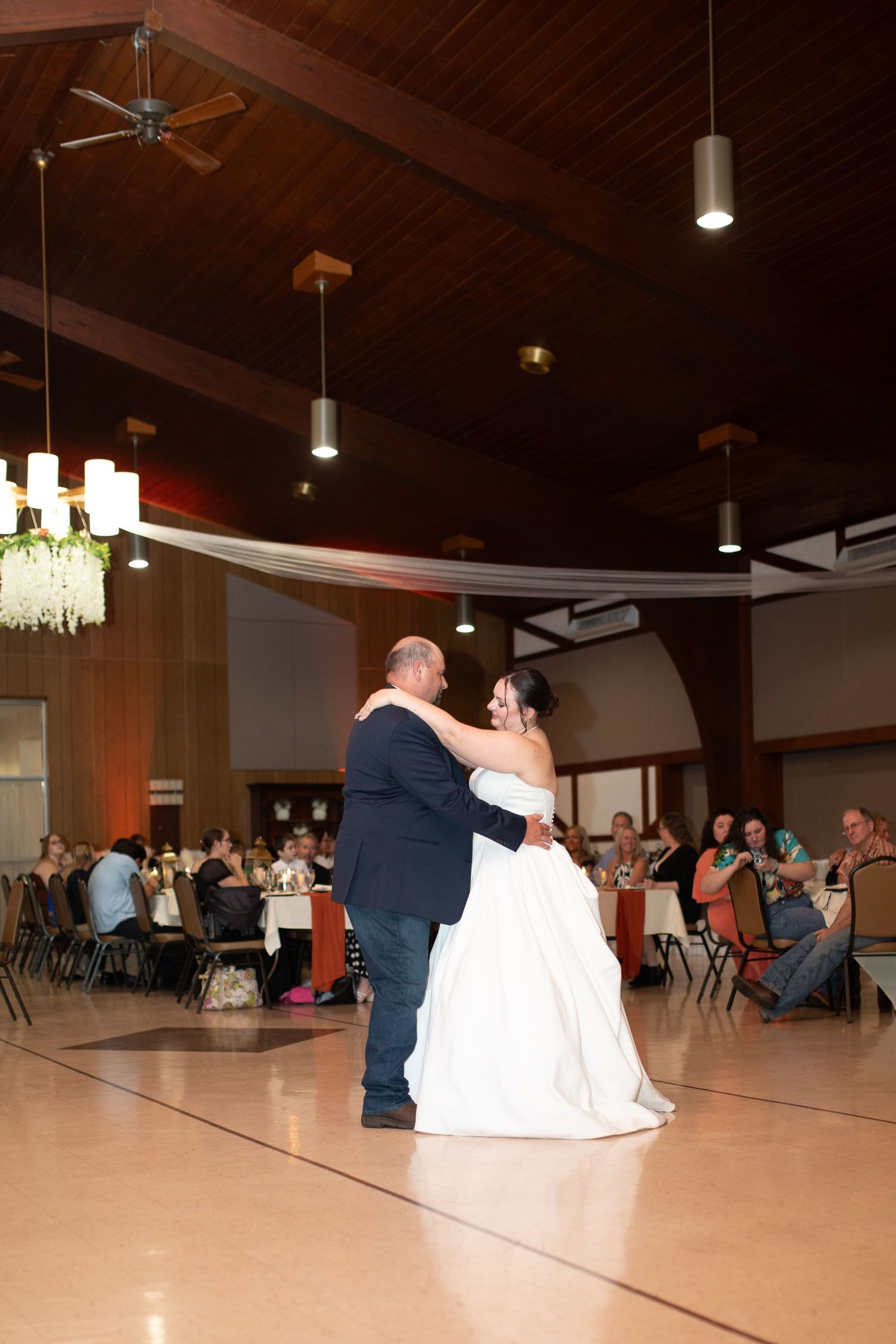 Panoramic view of a wedding reception dance floor with couple dancing in a large venue.
