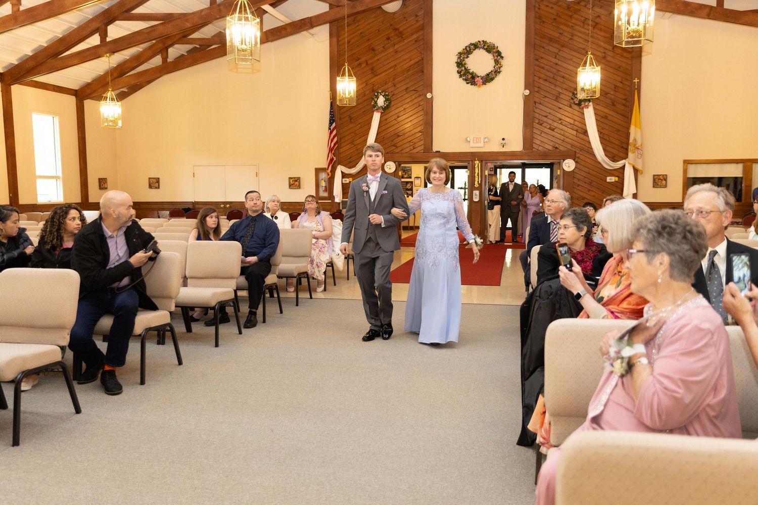 Elegant wedding ceremony in a wood-paneled chapel with guests seated as couple walks down the aisle.