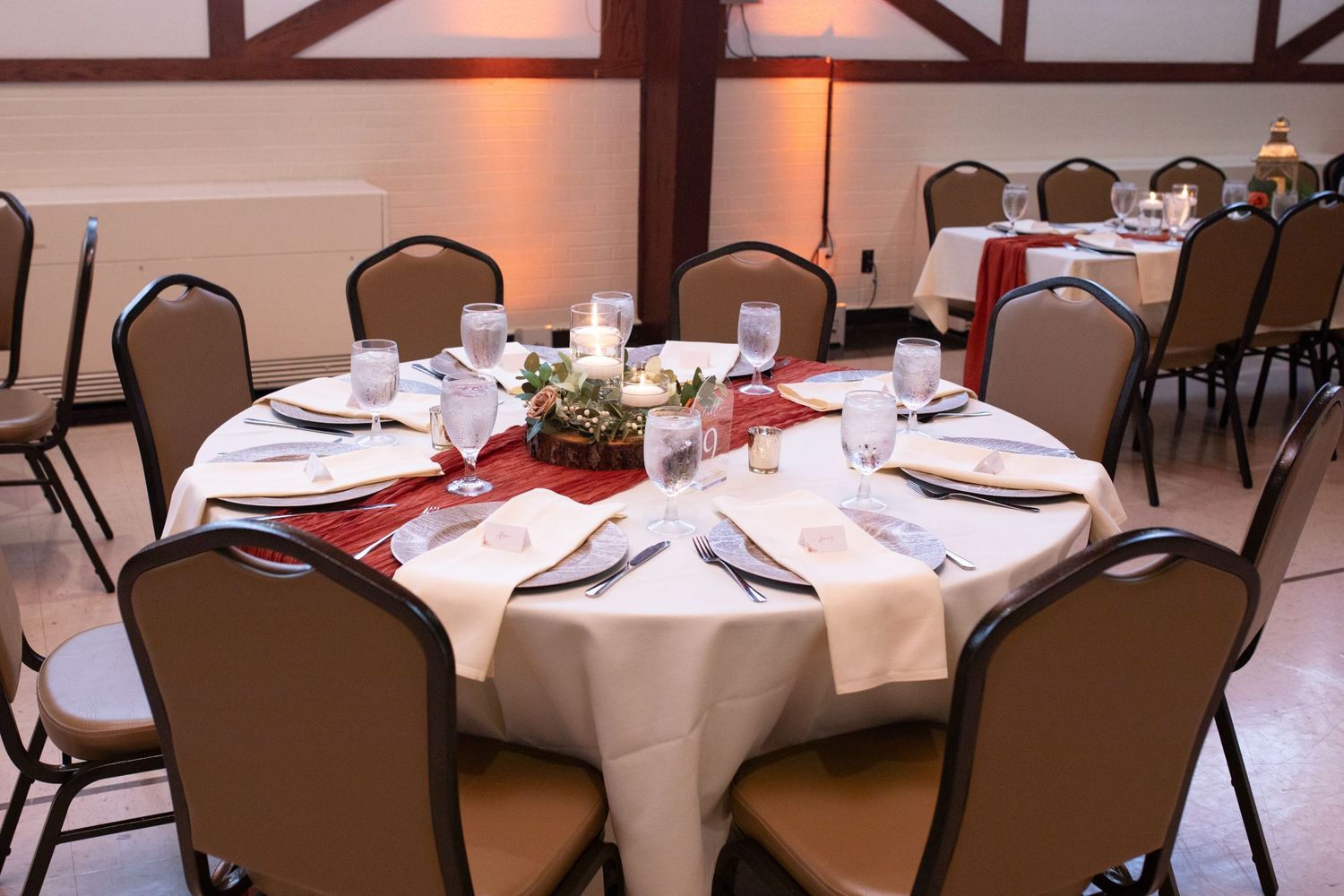 A round reception table with white linens and gold lantern centerpiece.