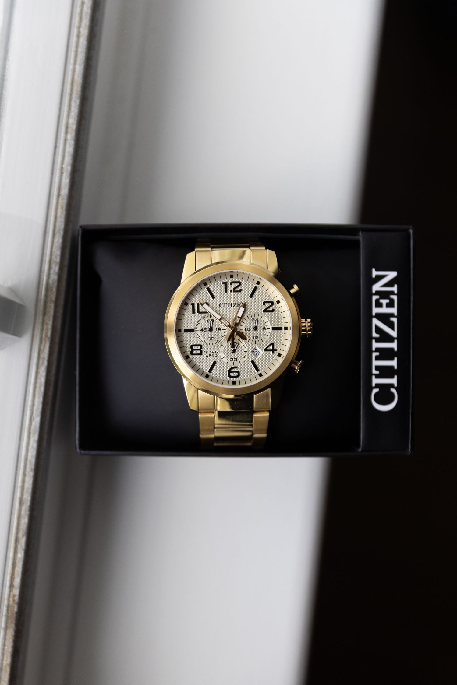 Gold luxury watch with chronograph features displayed in black box.