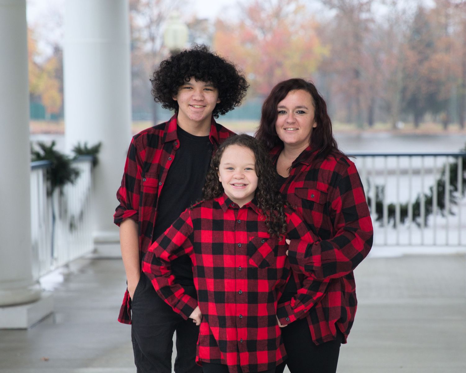 Holiday family photoshoot with matching buffalo plaid outfits on a classic white porch.