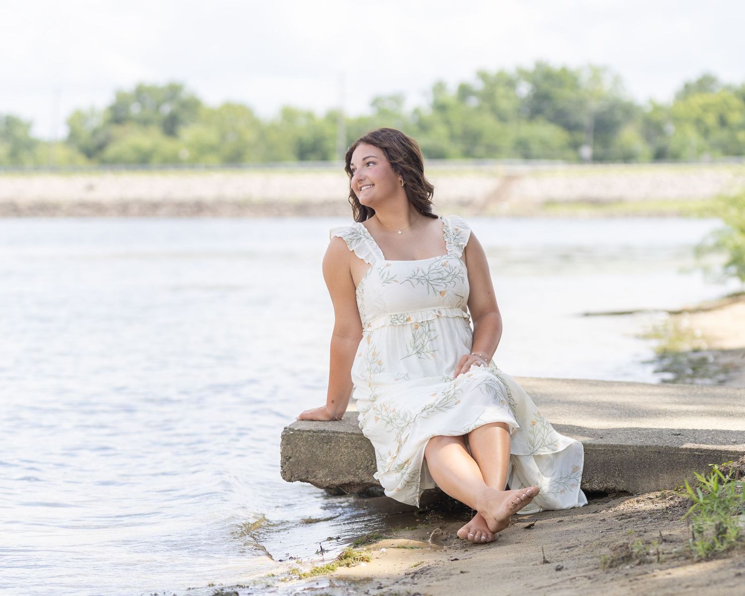 Scenic waterfront photo session featuring a white lace dress against a natural landscape.