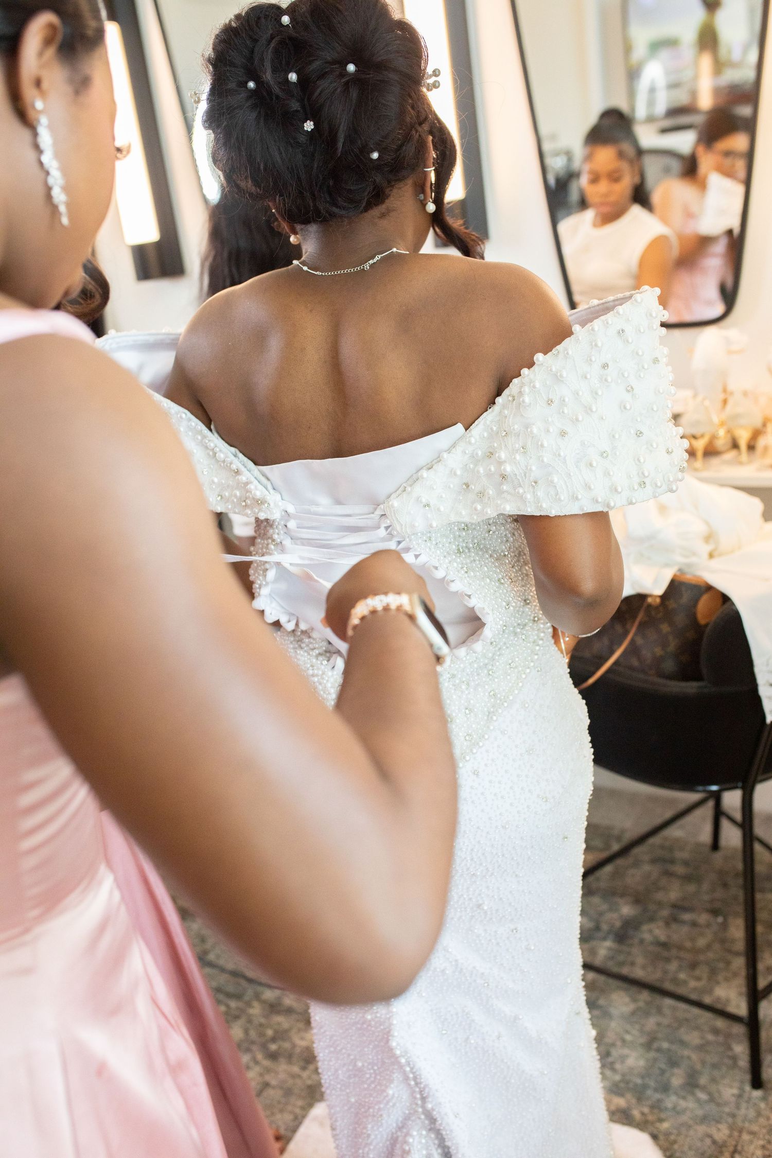 Wedding party members in white and pink dresses prepare for the ceremony.