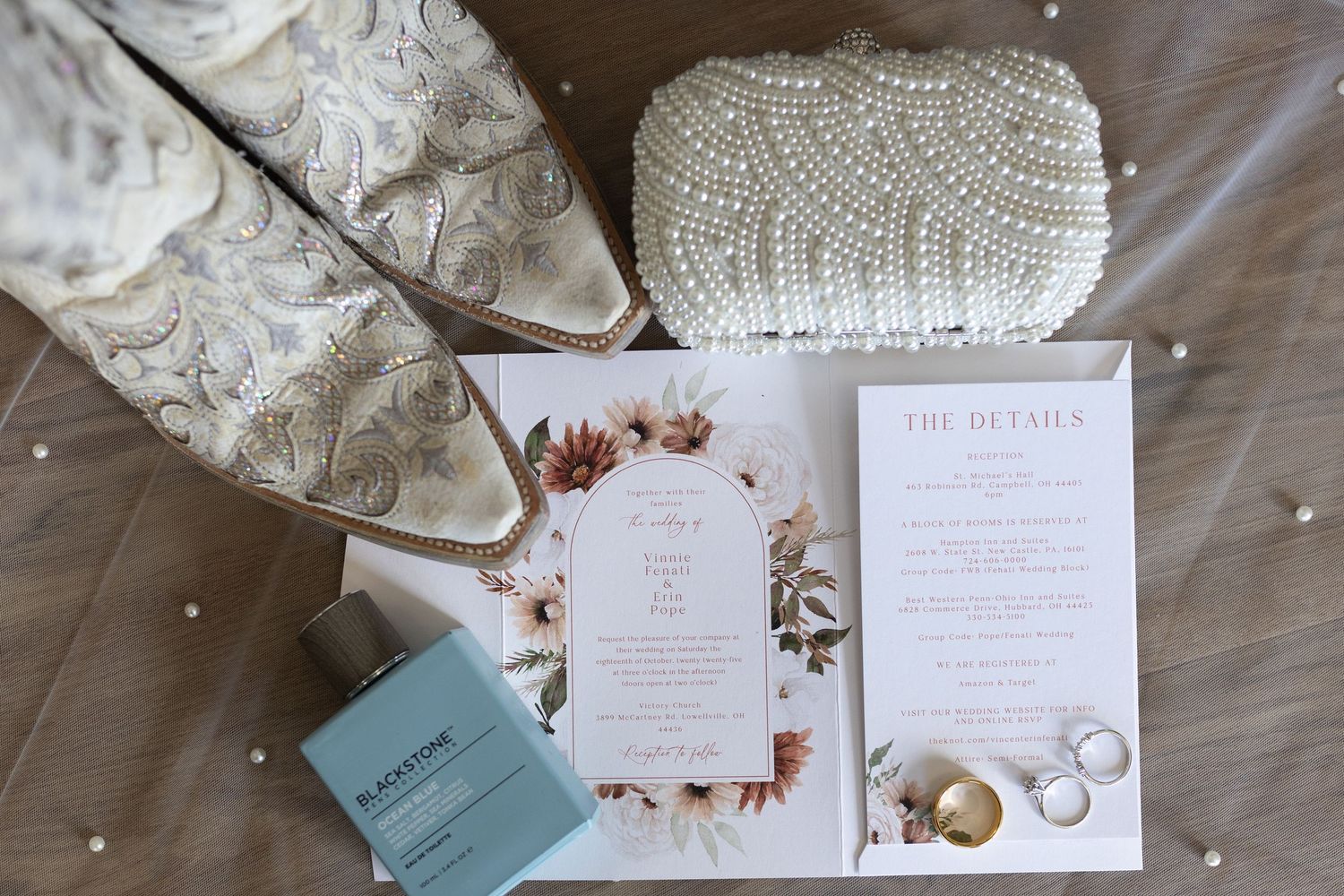 Wedding invitation suite with floral designs and watercolor details laid out on textured surface.