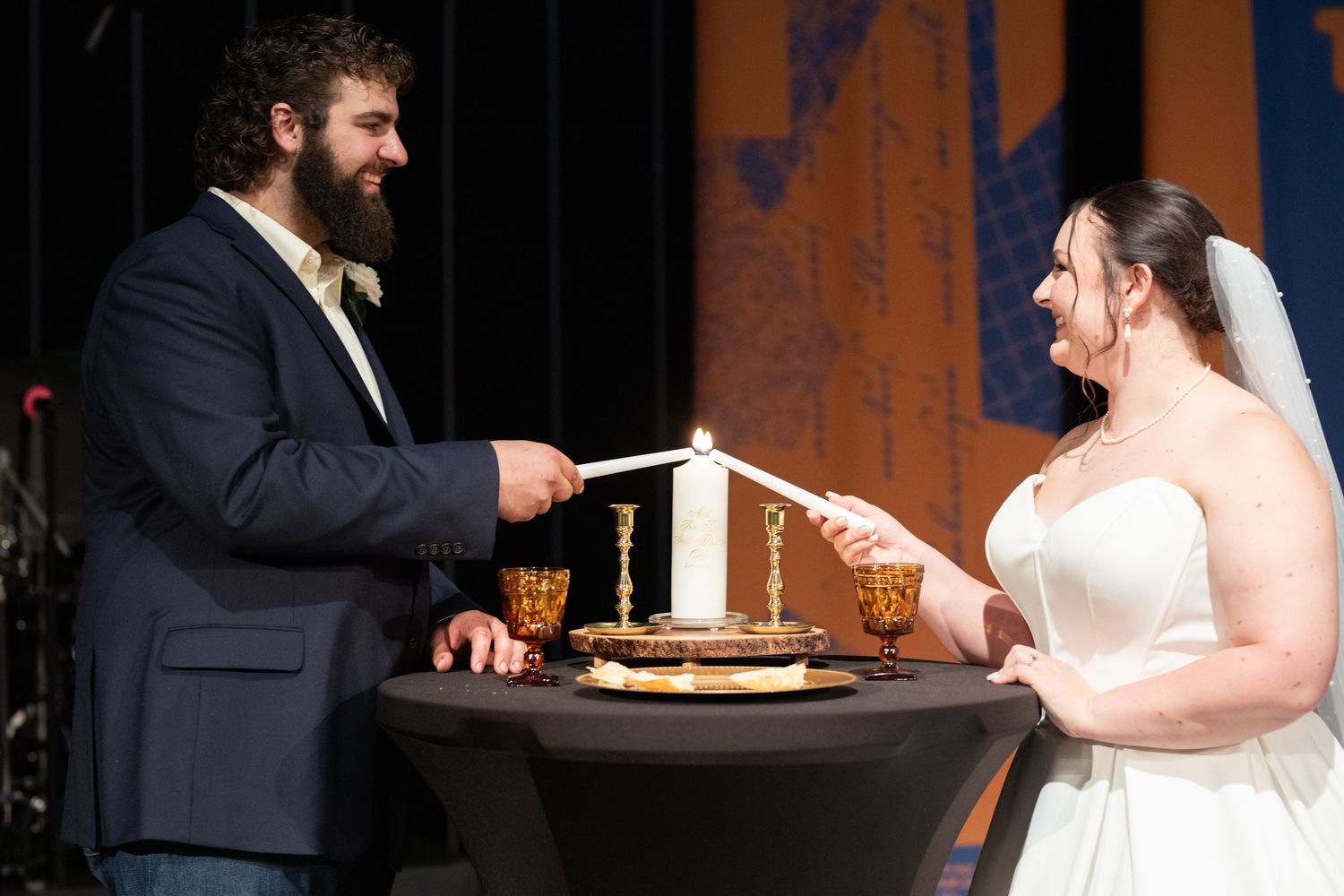 Couple participates in unity candle lighting ceremony during wedding service.
