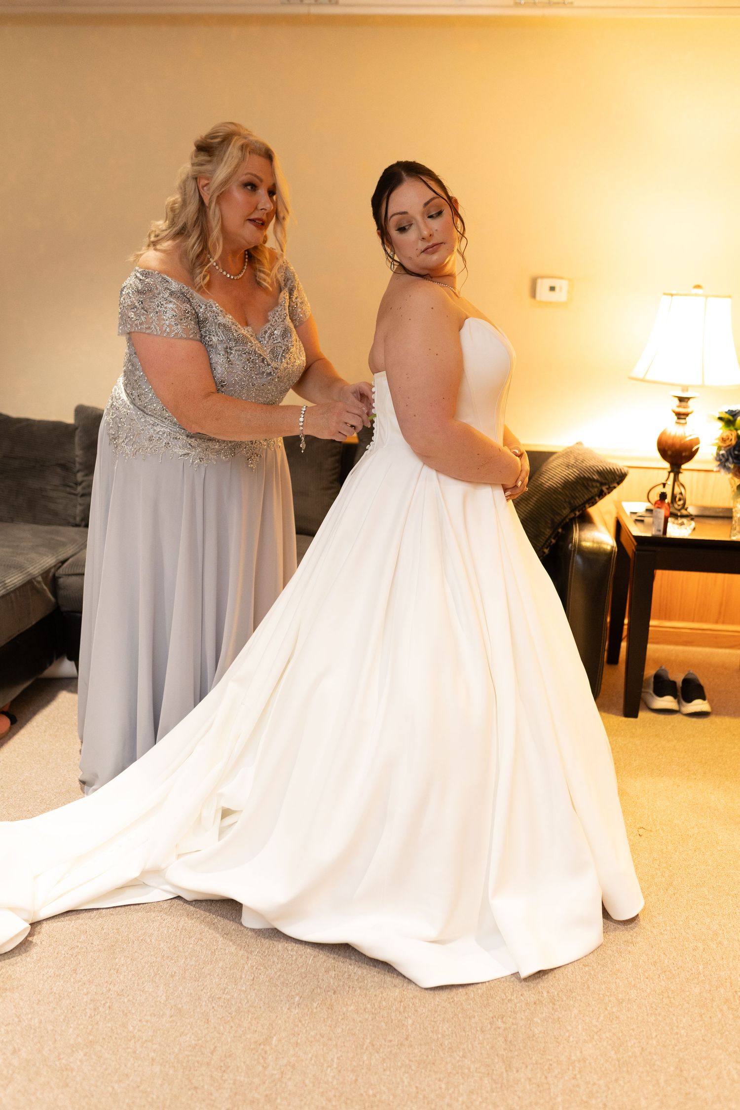 Wedding dress preparation scene showing the flowing white gown being adjusted.