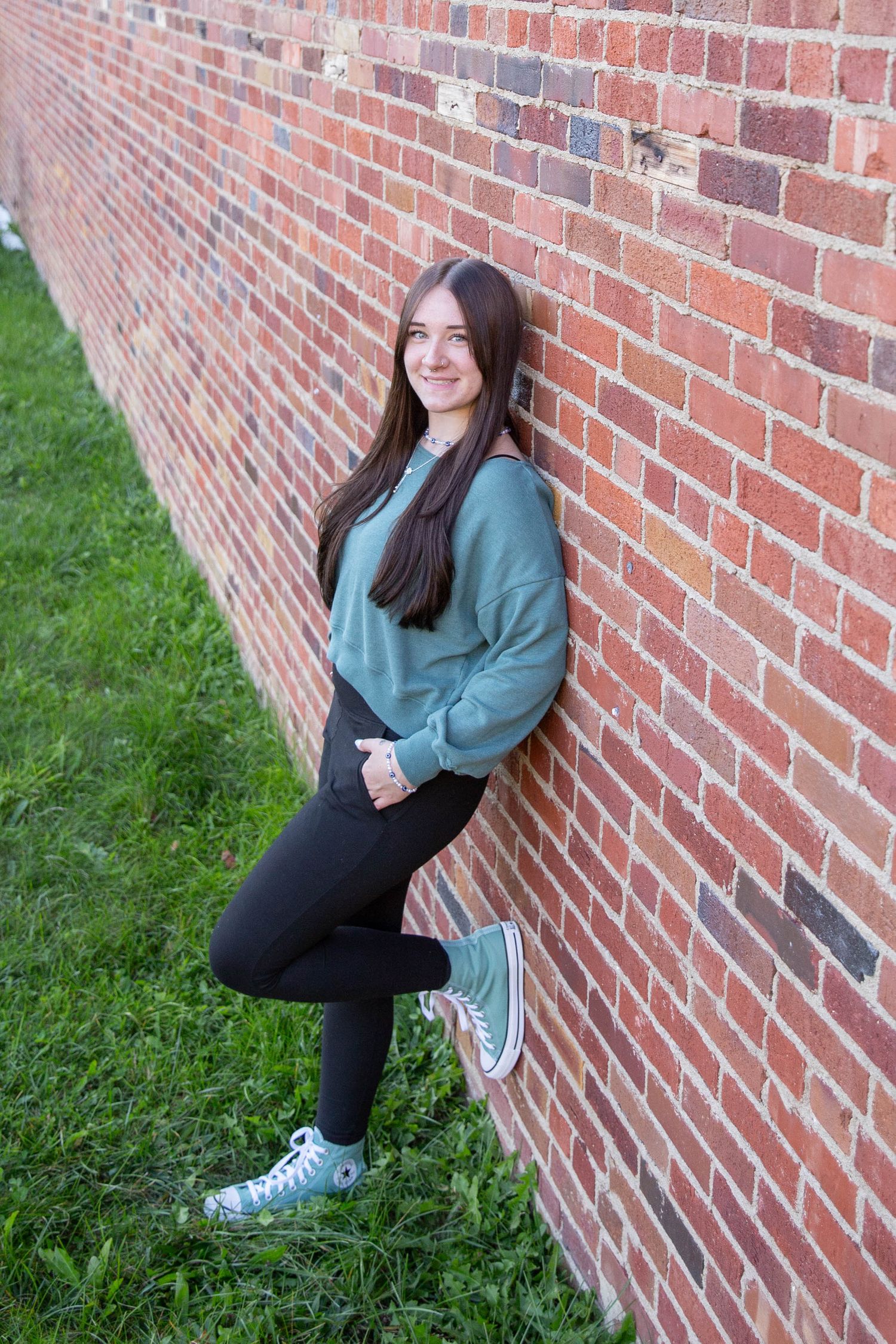 Portrait series against a red brick wall with grass and casual attire.