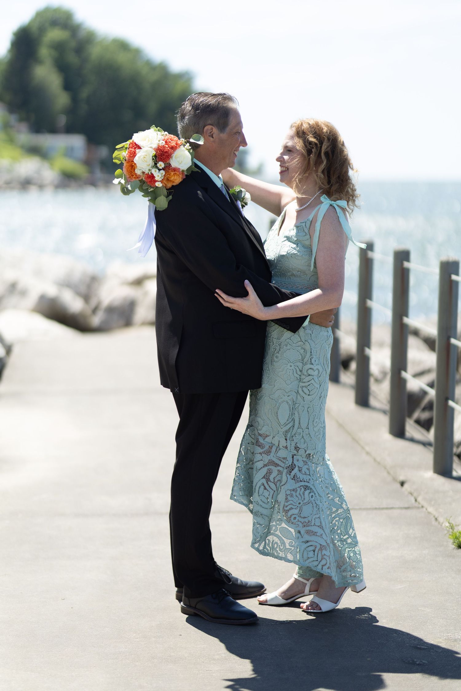Newlyweds sharing a romantic moment on a lakeside pier.