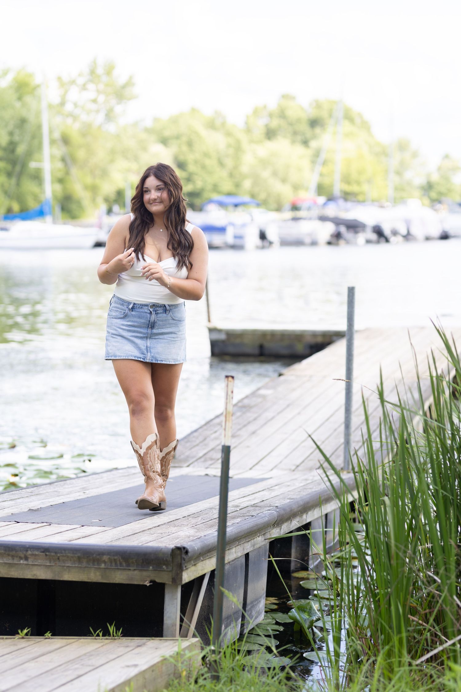 Standing on a wooden dock by a marina wearing western boots and summer attire.