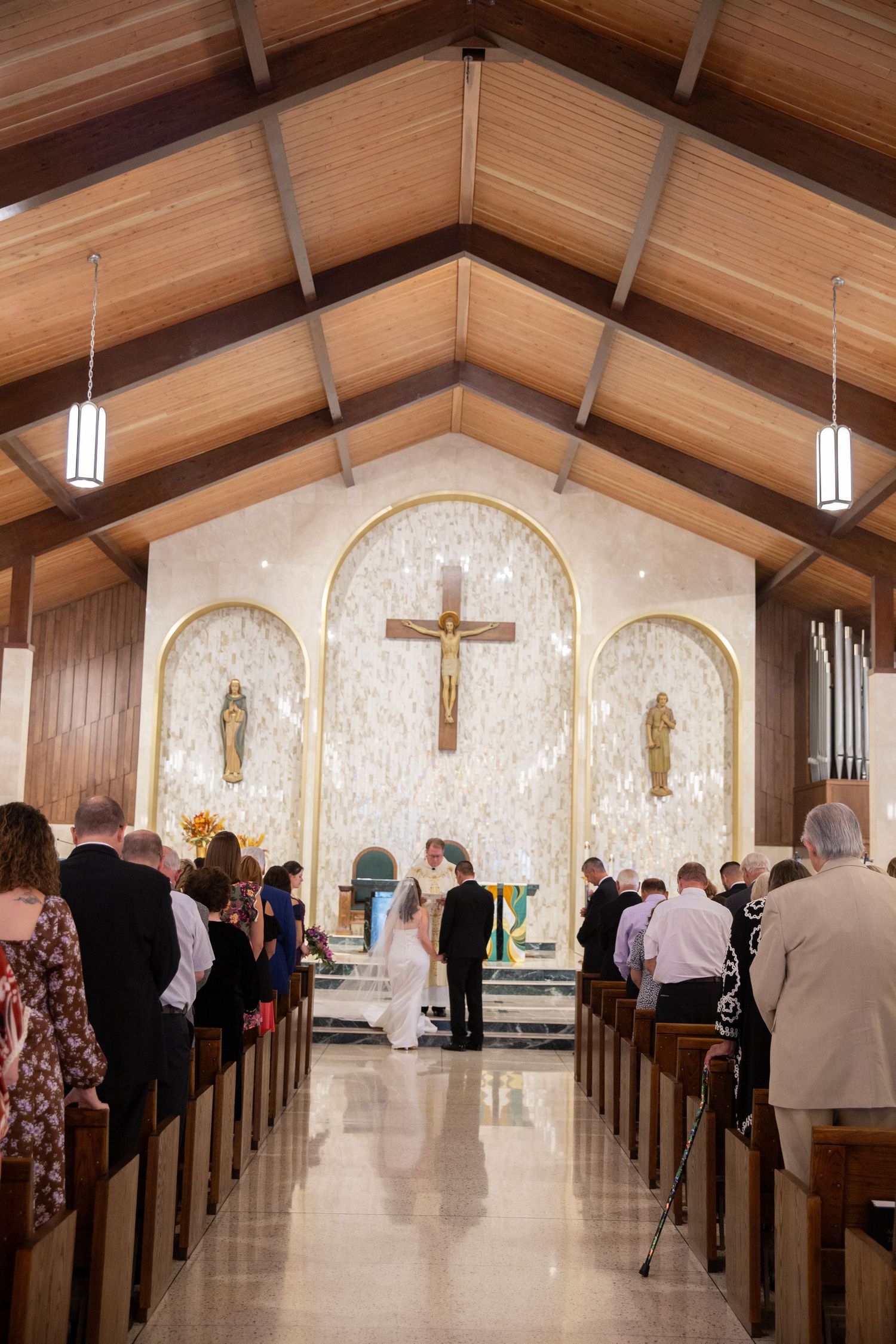 Interior of a Catholic church with wooden beams and pews during a wedding ceremony.
