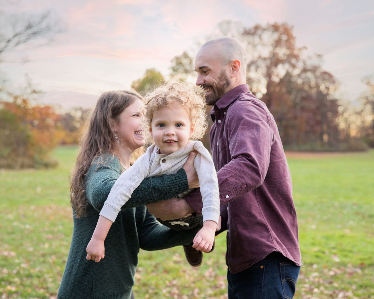 Playful family moments captured in a grassy field during golden hour.
