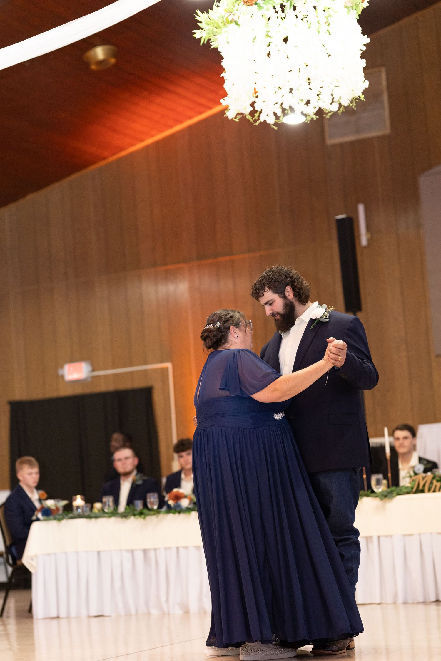 Wedding party members in navy dresses dance during reception celebration.