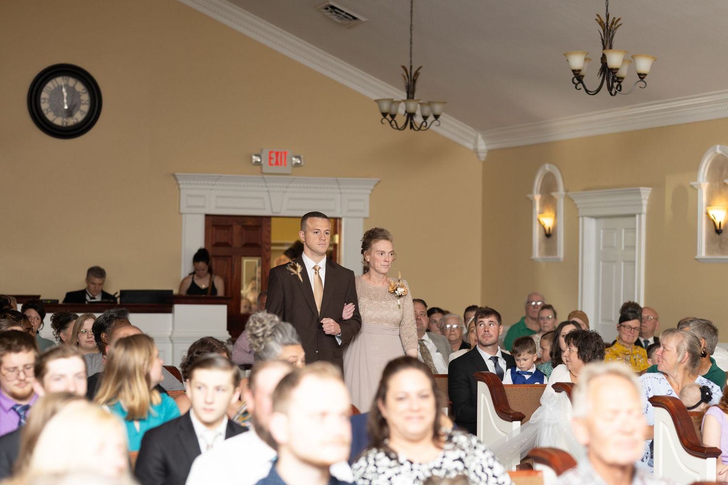 Wedding celebration in a traditional hall with chandelier and gathered guests.