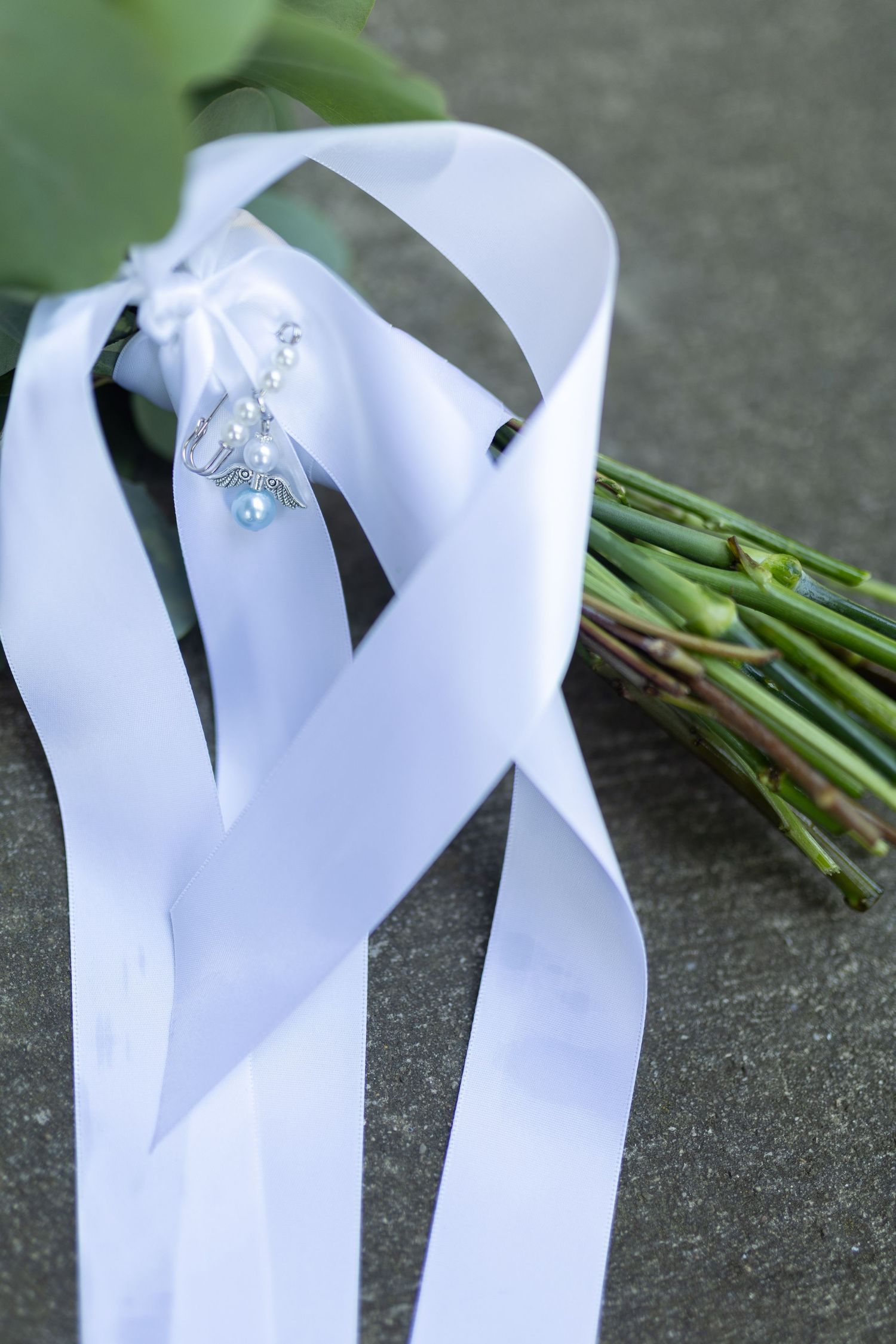 White satin ribbon with crystal decoration next to a flower stem bouquet.