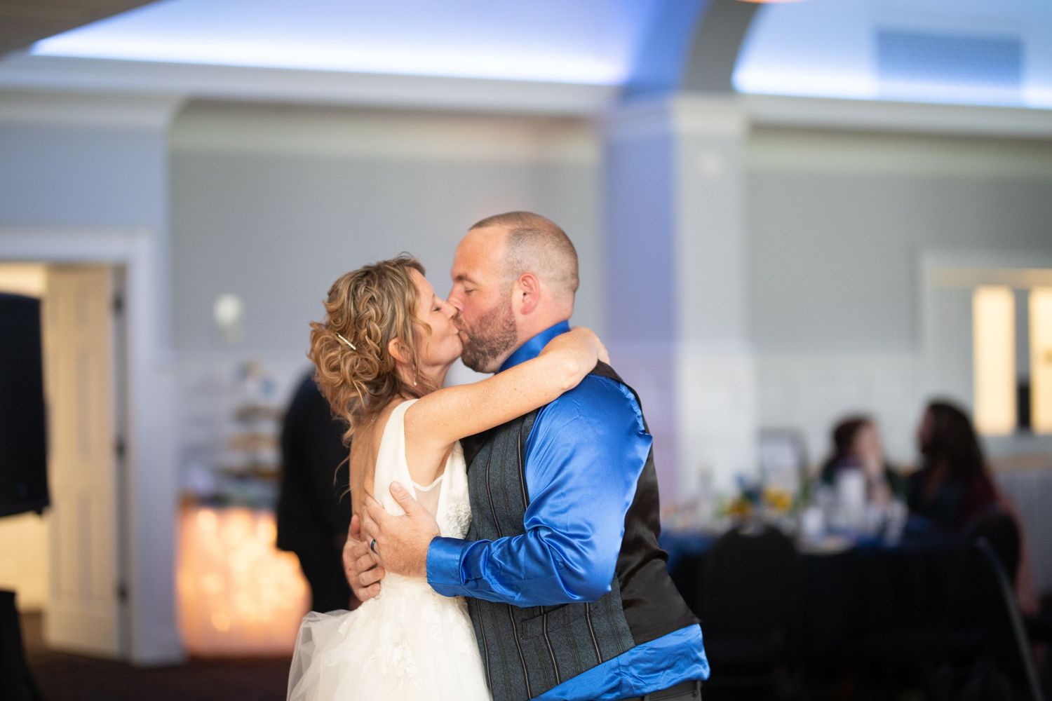 Bride and groom share a romantic first dance kiss at their wedding reception in an elegant venue.