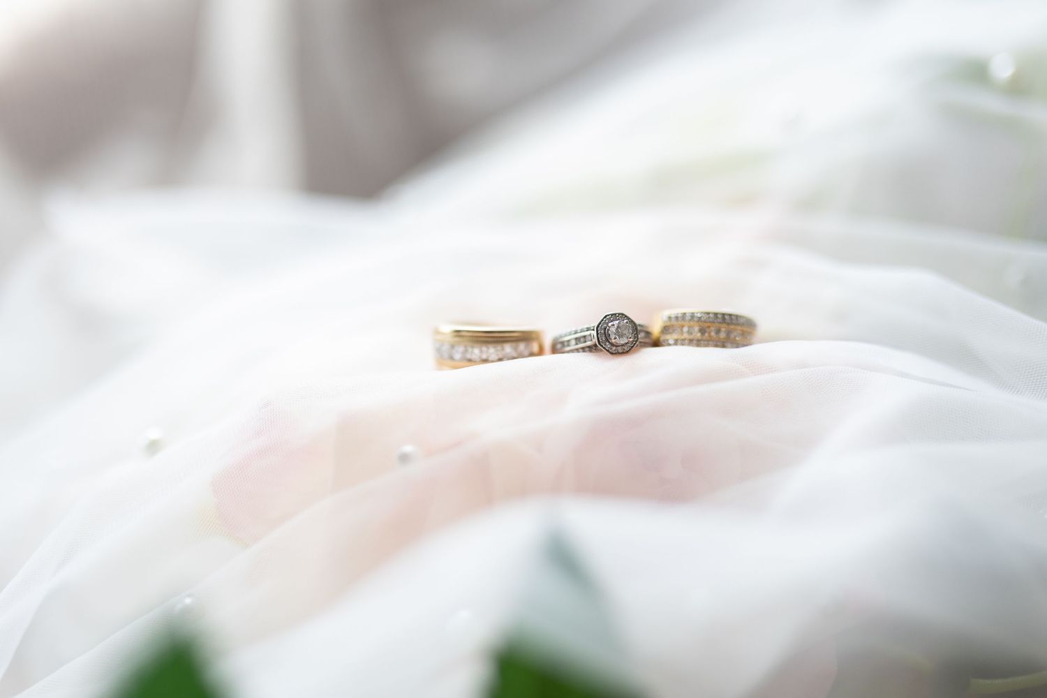 A close-up shot of a wedding ring resting on white fabric with soft focus.