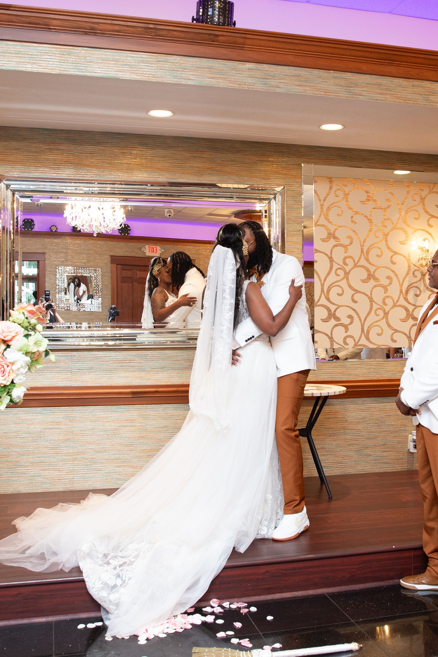 Wedding celebration in elegant ballroom with mirrored walls and chandelier lighting.