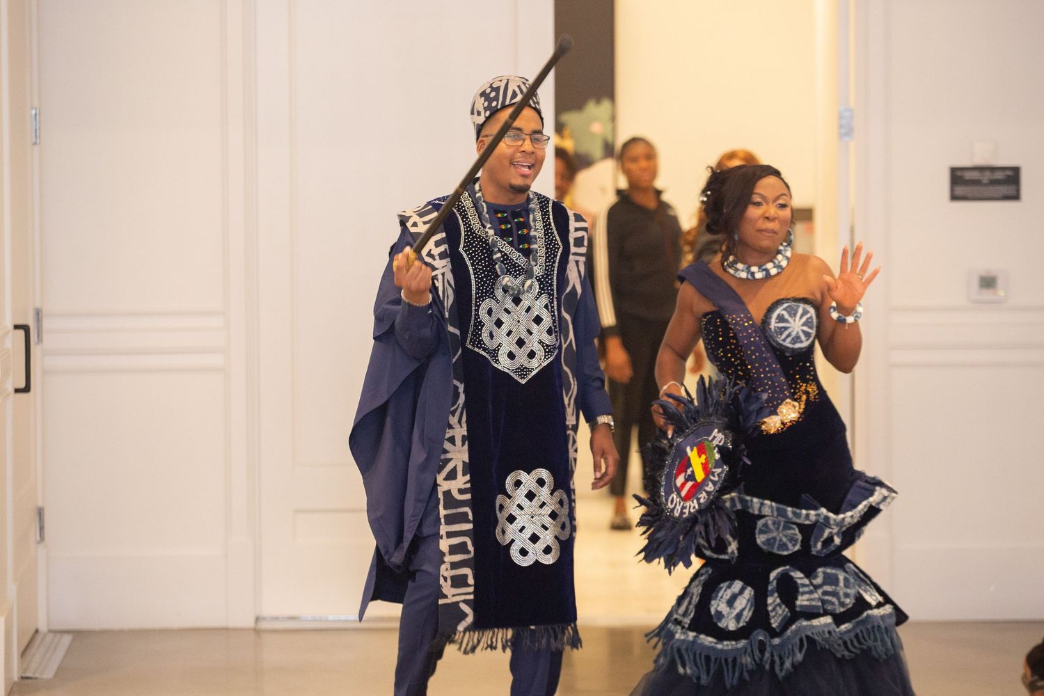 Couple in coordinated navy and white patterned outfits posing in an elegant hallway.