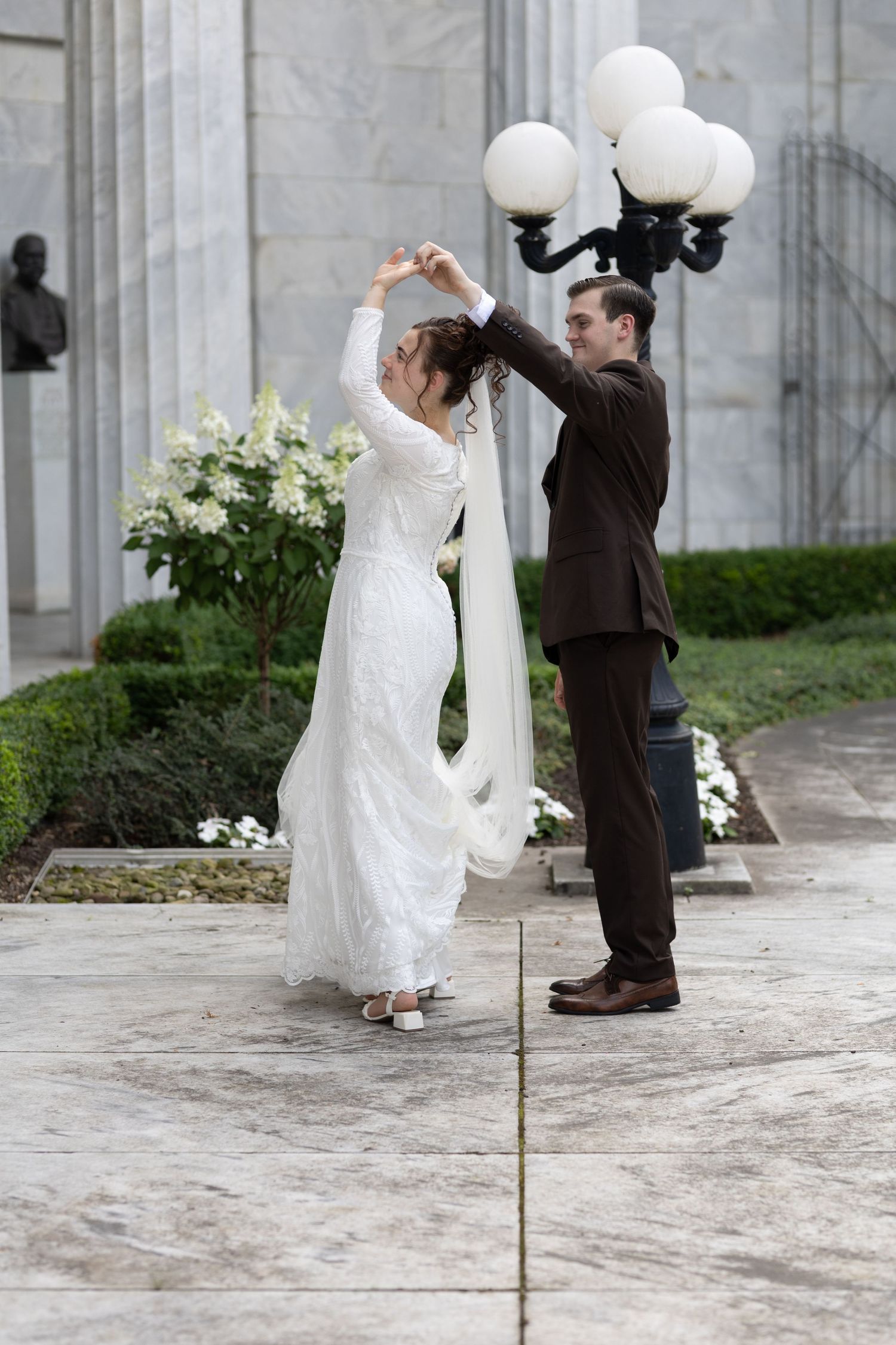 Couple dances together on marble terrace by vintage lamp post.