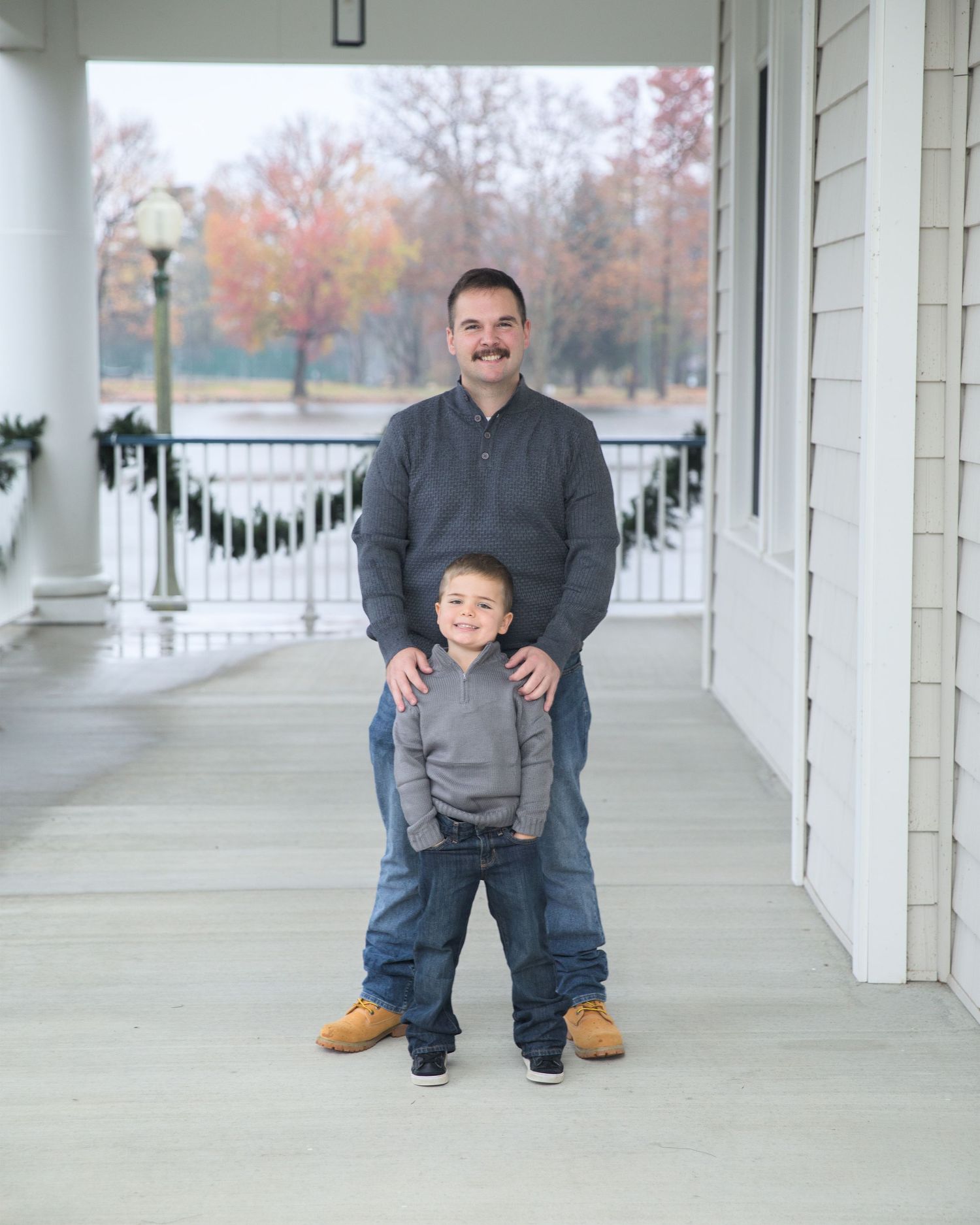 Casual portrait session on a white columned porch with fall colors in the background.