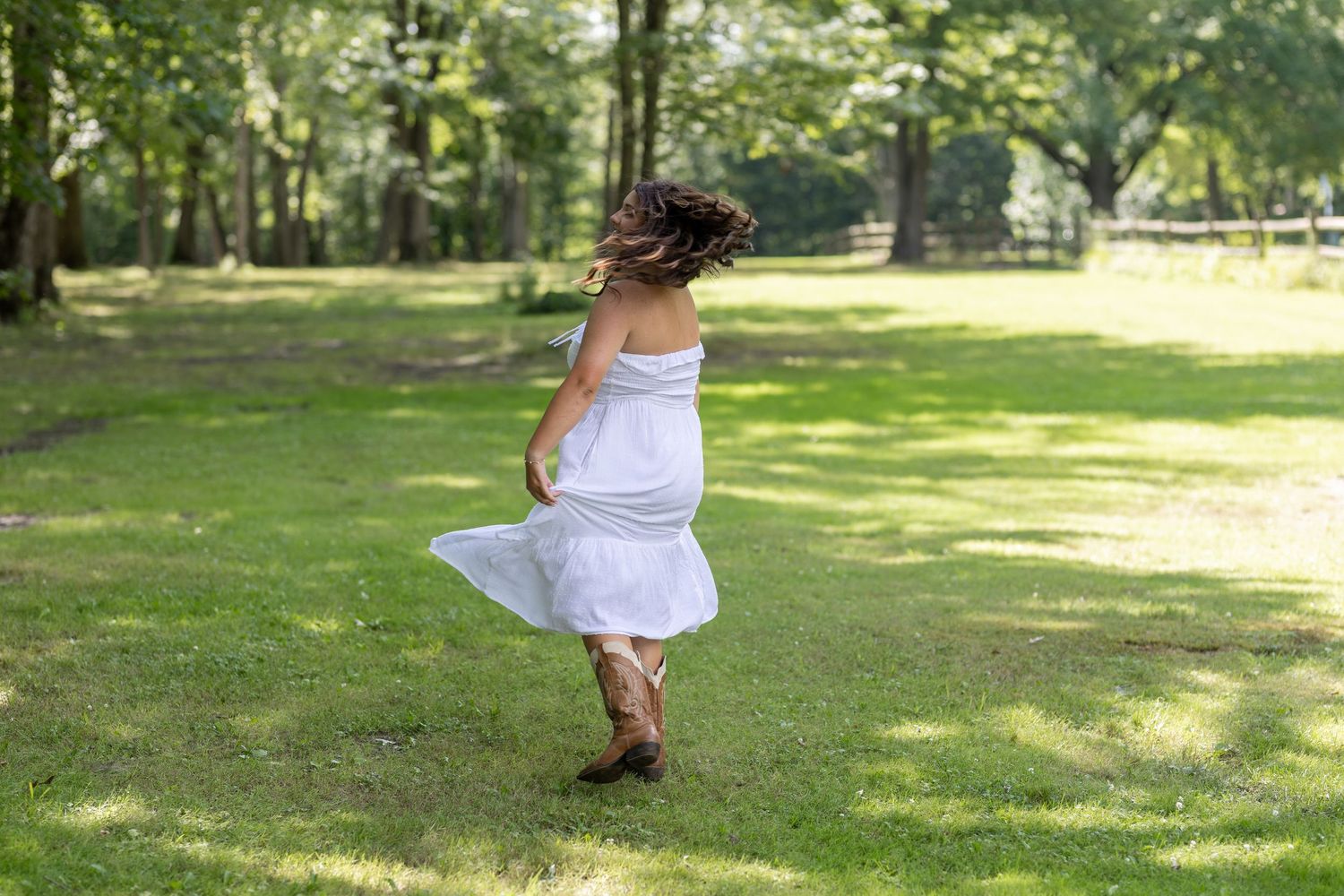 A playful white dress twirls in motion against a sunlit green park background.