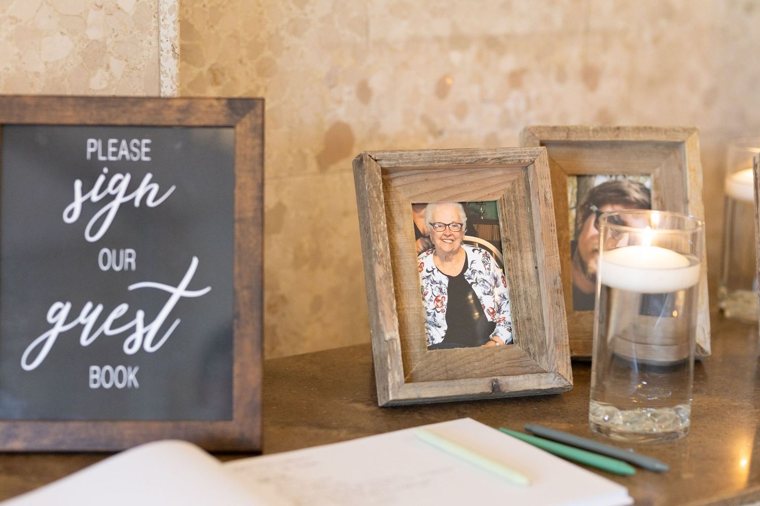 A guest book sign with rustic wooden frames and candle decor.